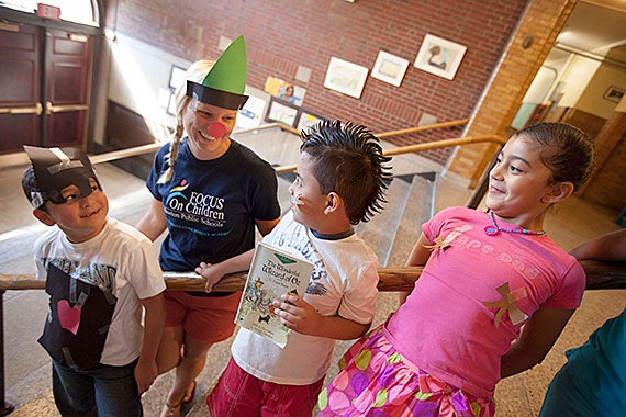 Student Denny Diaz, (from left) McKay School teacher, Brianna Guilford (green triangle hat), Andy Reyes, and Carol Cruz  perform an activity based on the Wizard of Oz book read in class as part of the Pretext program inside the McKay School in East Boston. The program began at Harvard and has been implemented in Boston Public Schools' English Language Learners summer school programs. Kris Snibbe/Harvard Staff Photographer