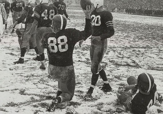 Edward Kennedy (No. 88) raises the ball after a score. Snow covered the field at Harvard Stadium during the 1955 matchup. Courtesy of Harvard University Archives