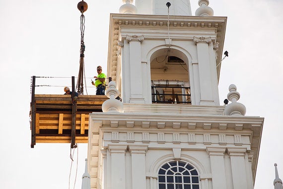 A team of three workers eases the old bell onto a special platform attached to the Memorial Church spire. 