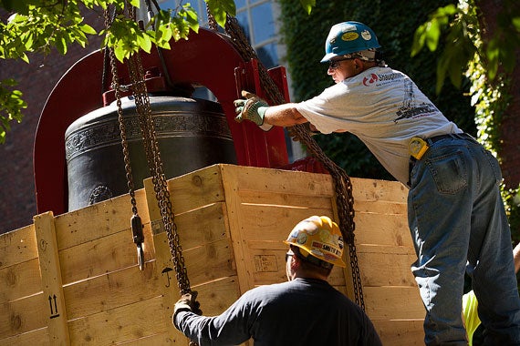 Workers slowly ease the new bell, which weighs nearly 5,000 pounds, out of a wooden crate. 