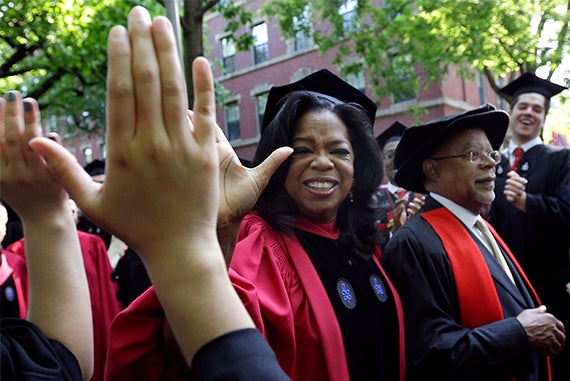 Oprah Winfrey high-fives graduates as she walks with Henry Louis Gates Jr. during the procession. Photo by Elise Amendola/AP Photo