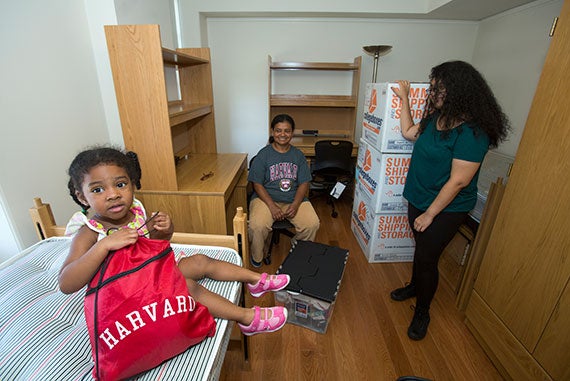 Jasmine McEacheron, 3, tries out a bed in the room of her aunt, Charity Barros '18 (right), as Charity's mother, Eucharis, shares in the moment.
