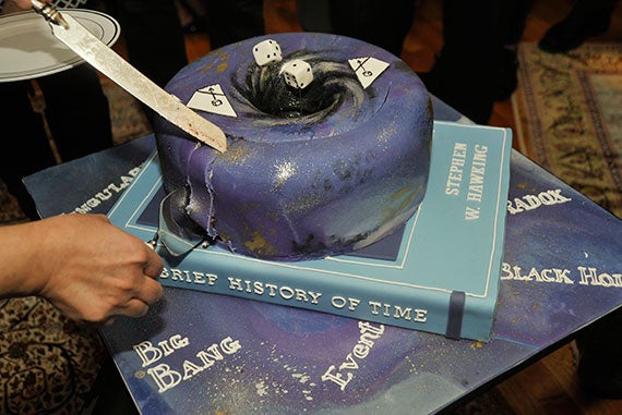 A cake of the cosmos — complete with a black hole — is cut after being presented to Hawking. 