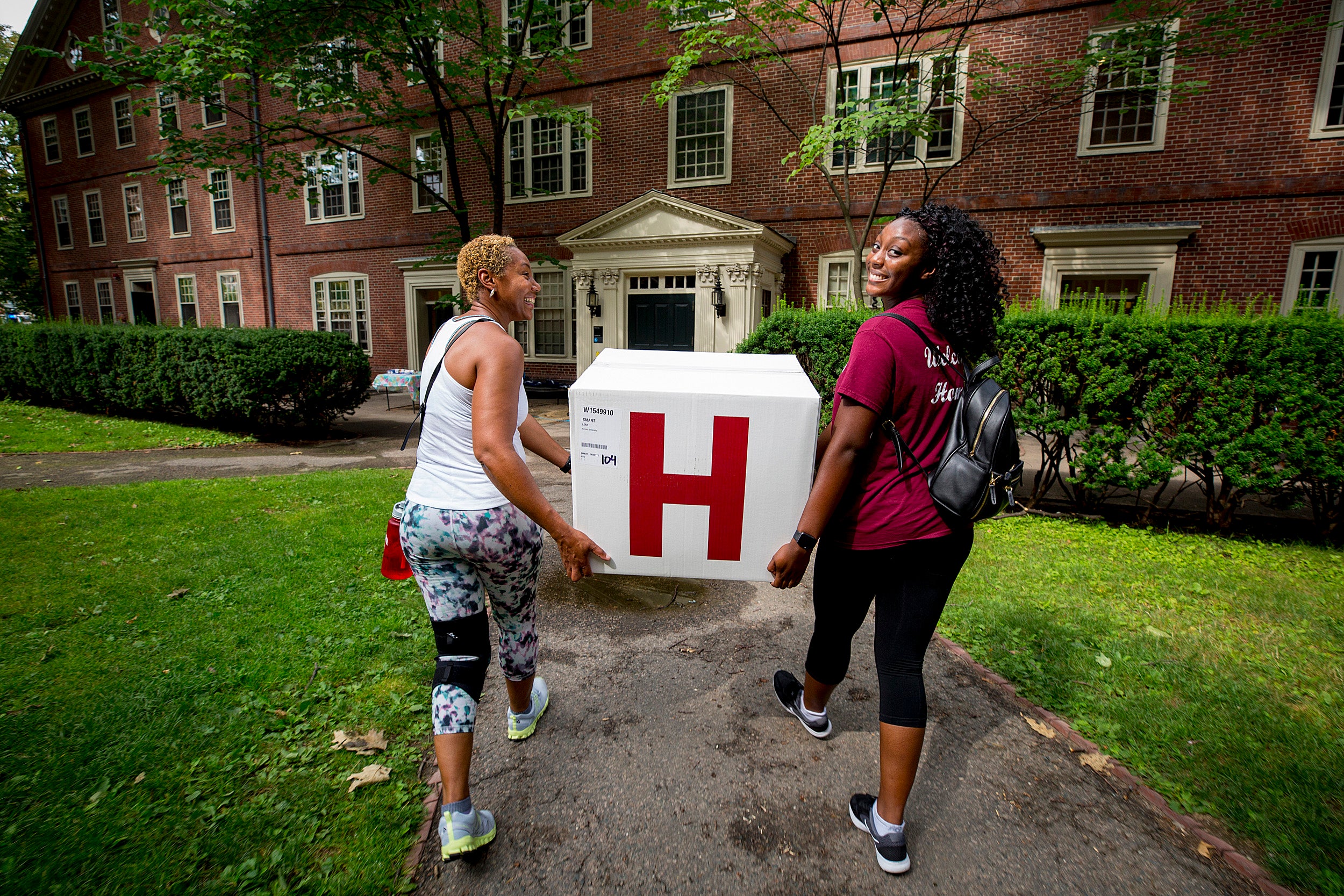 Freshman Leah Smart and her mother, Dee, carry box into Harvard dorm.