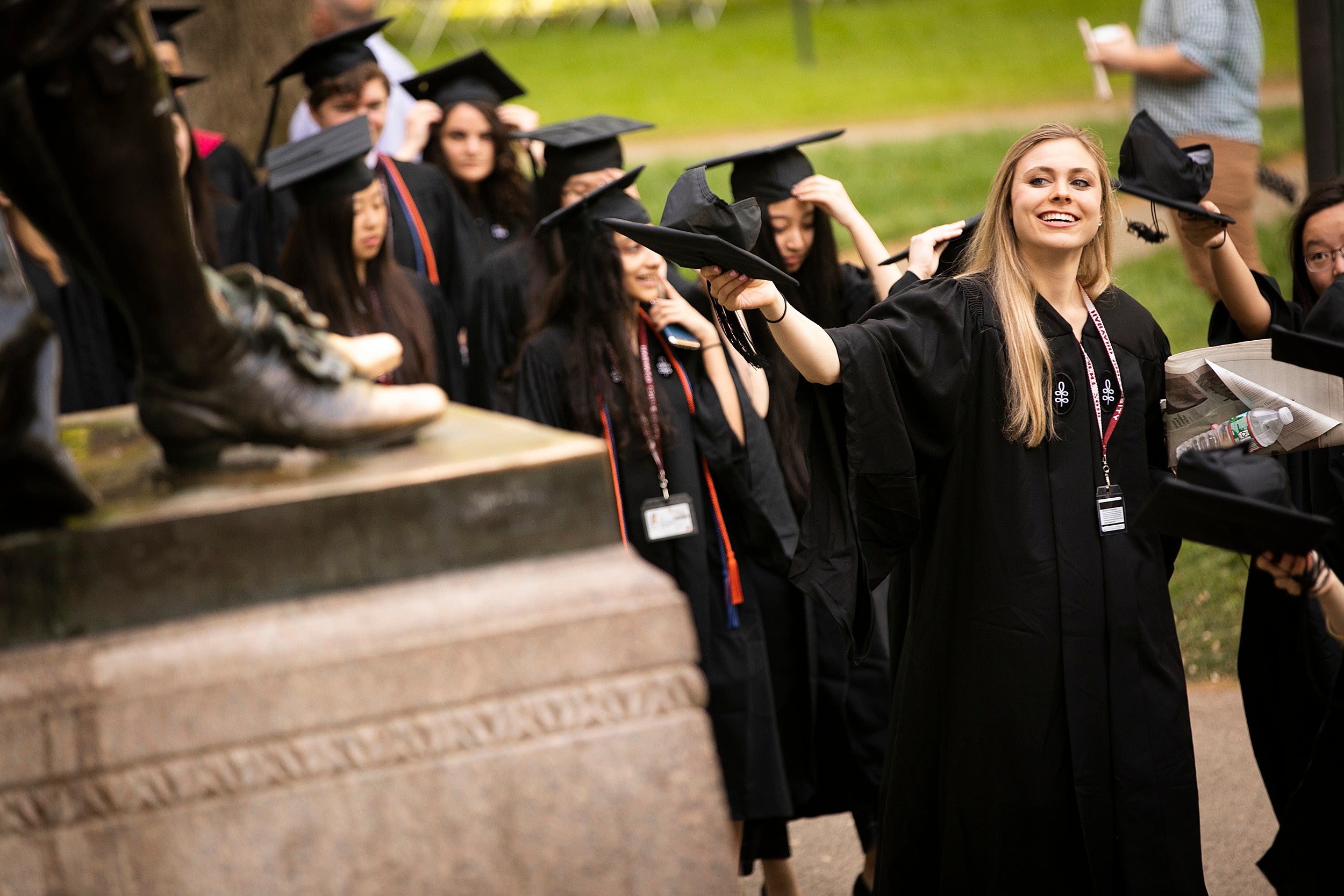 Graduates file past the John Harvard Statue.