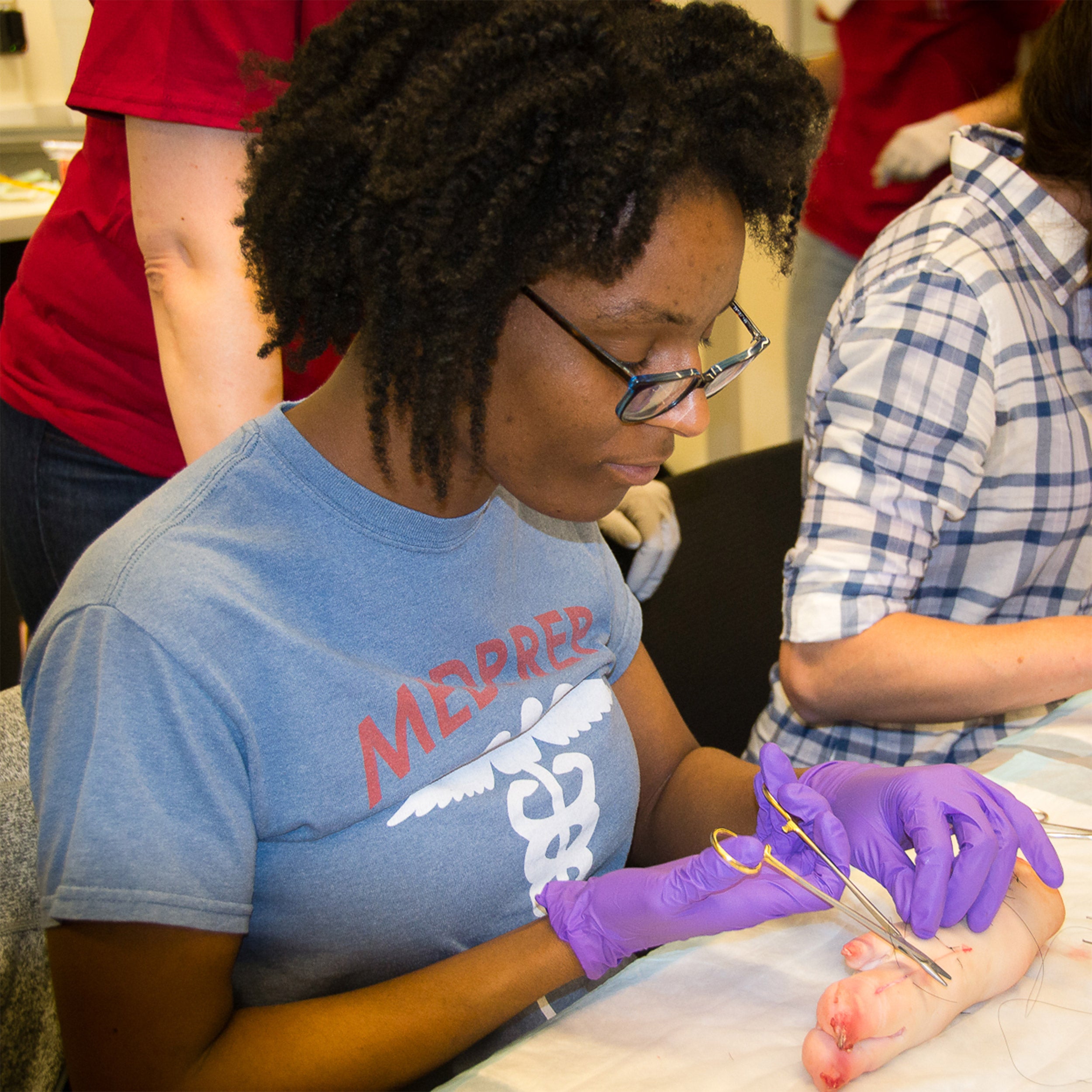 Trenika Williams learns suture techniques using a pig foot model.