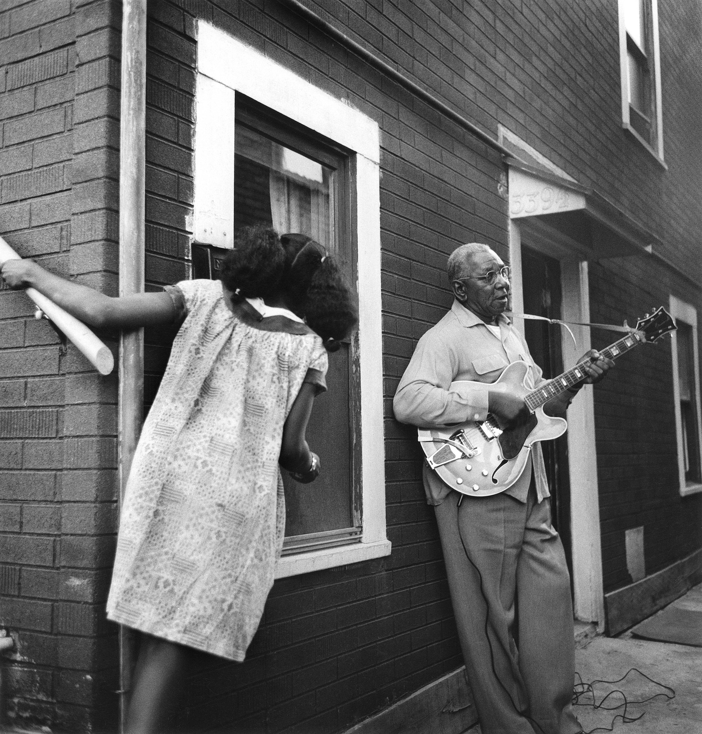 Girl watches man play guitar in 1965.