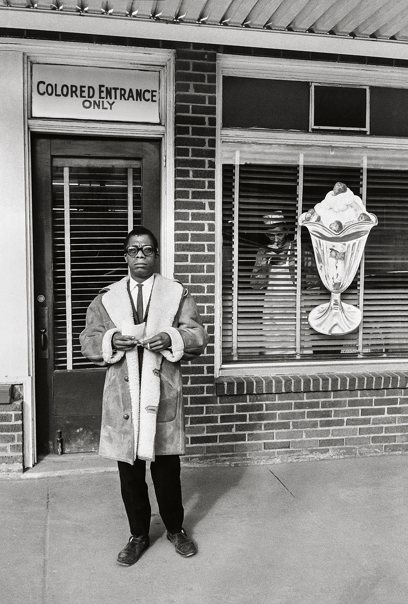 James Baldwin stands in front of "Colored entrance only" sign in New Orleans, 1963.