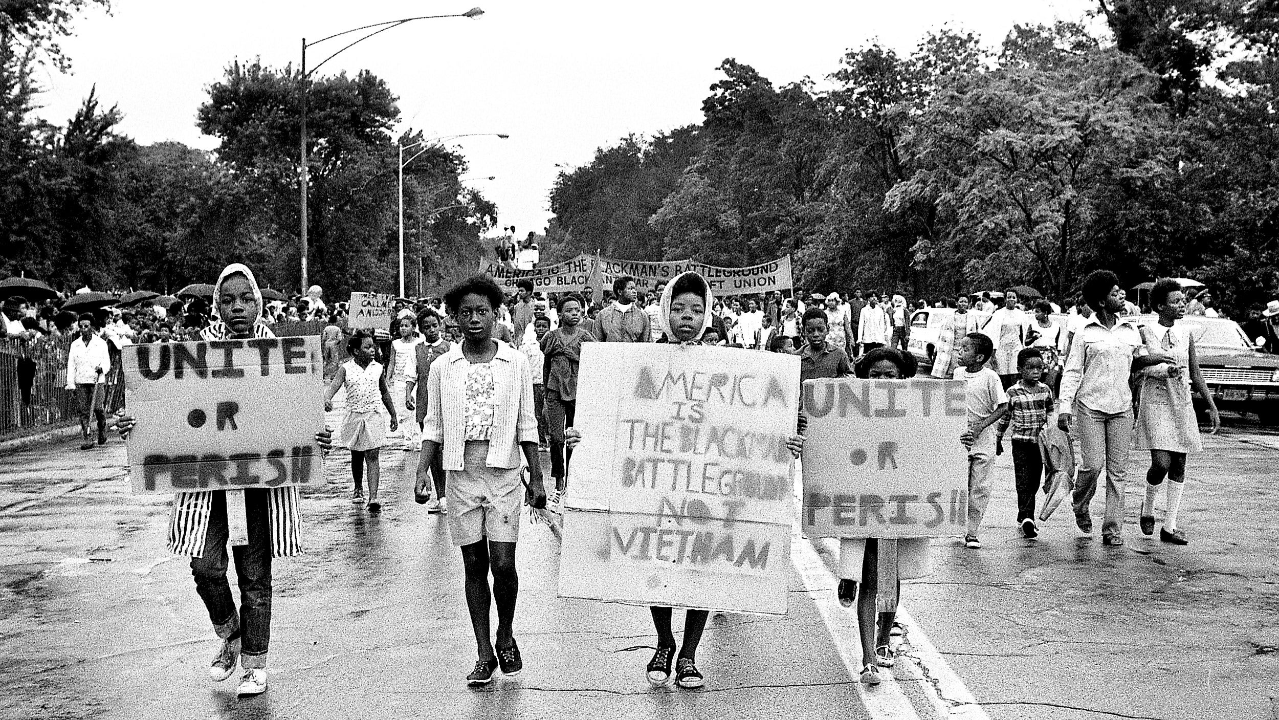 Vietnam War protesters march in Chicago in 1968 holding sign reading "Unite or perish."