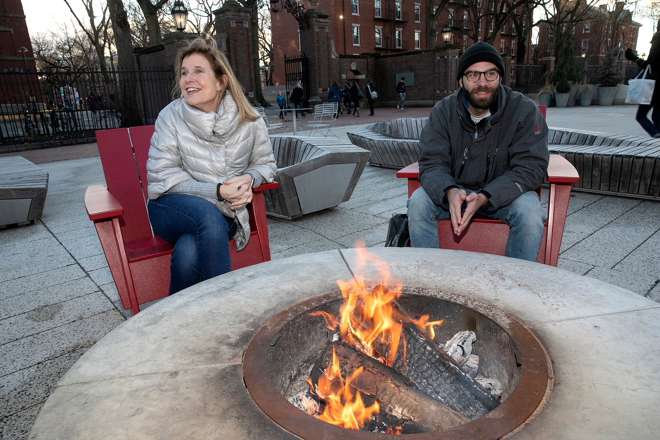 Two people sitting around a fire pit