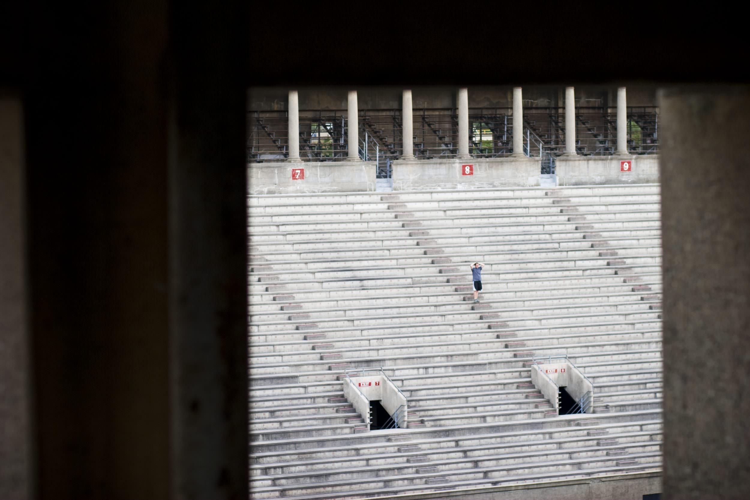 A runner stands on the steps of Harvard Stadium stairs.