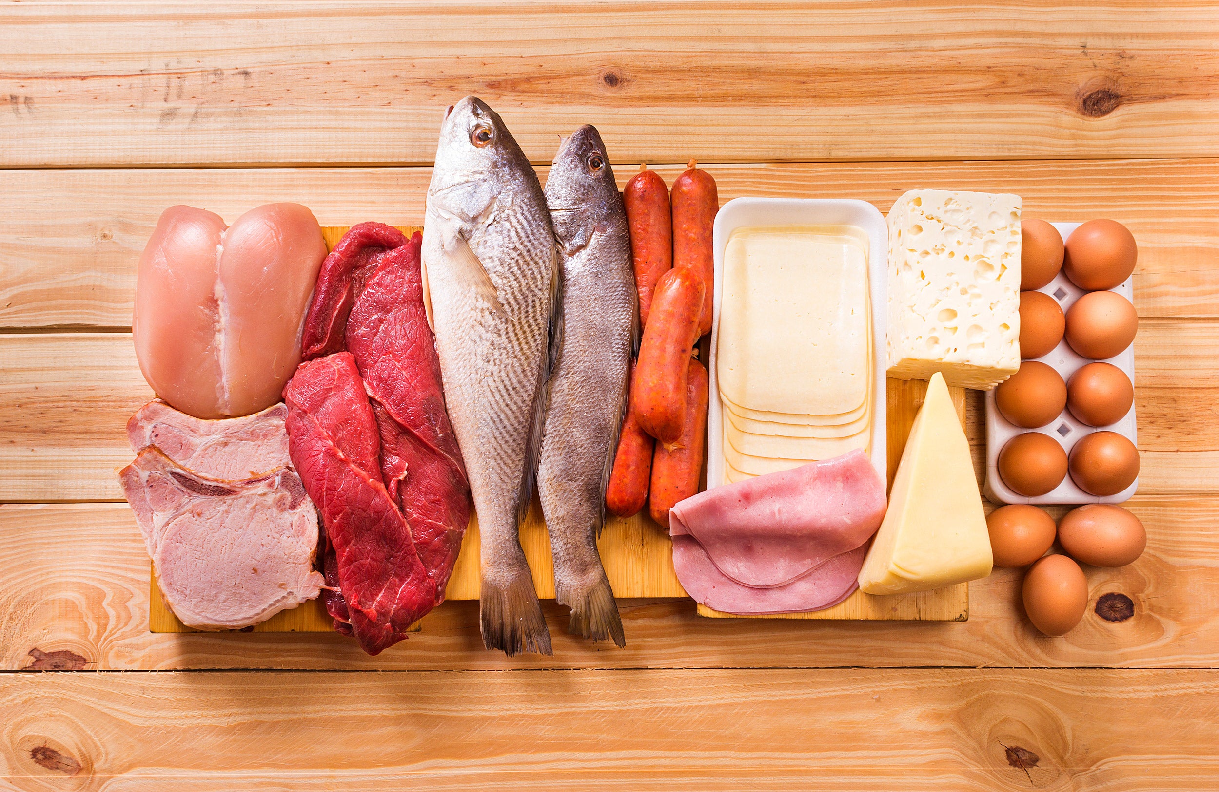 meats, fish, dairy, eggs, white meat on a wooden table as background