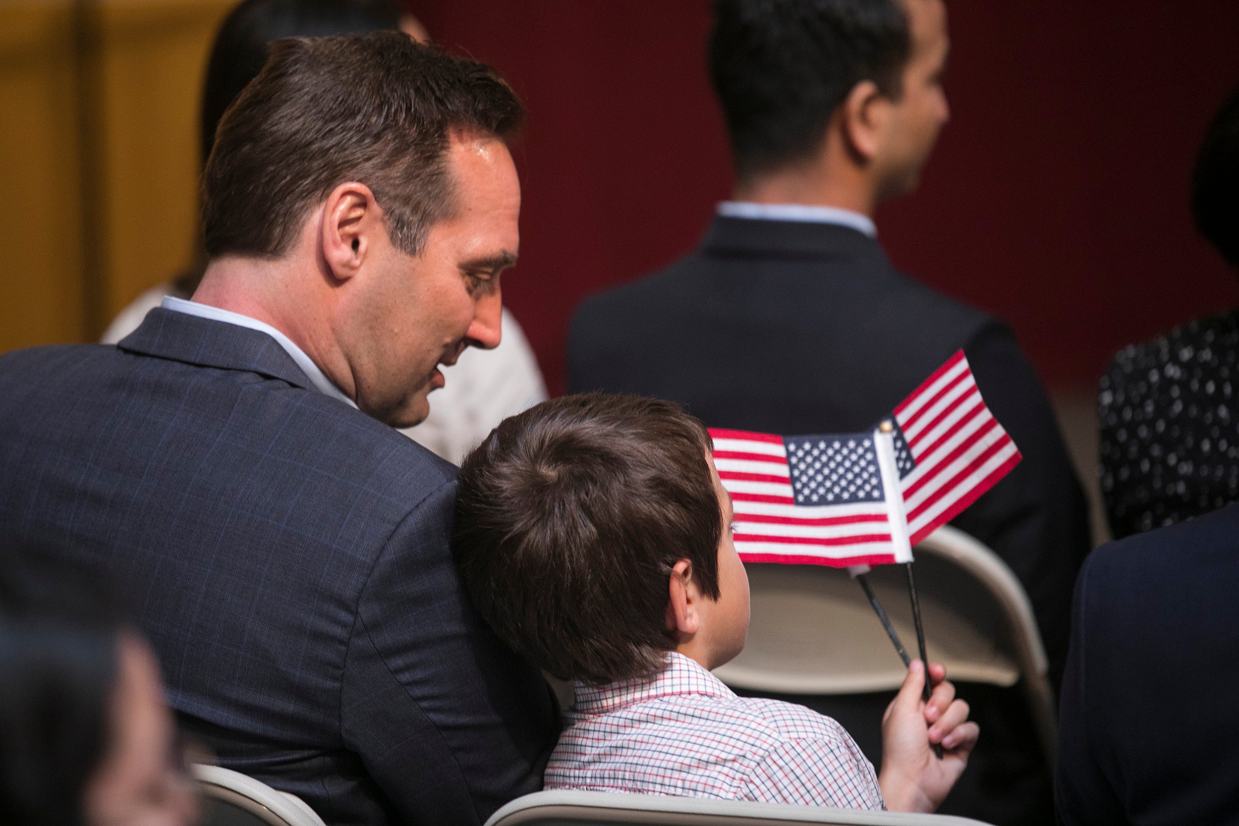 man sitting with son, holding American flag