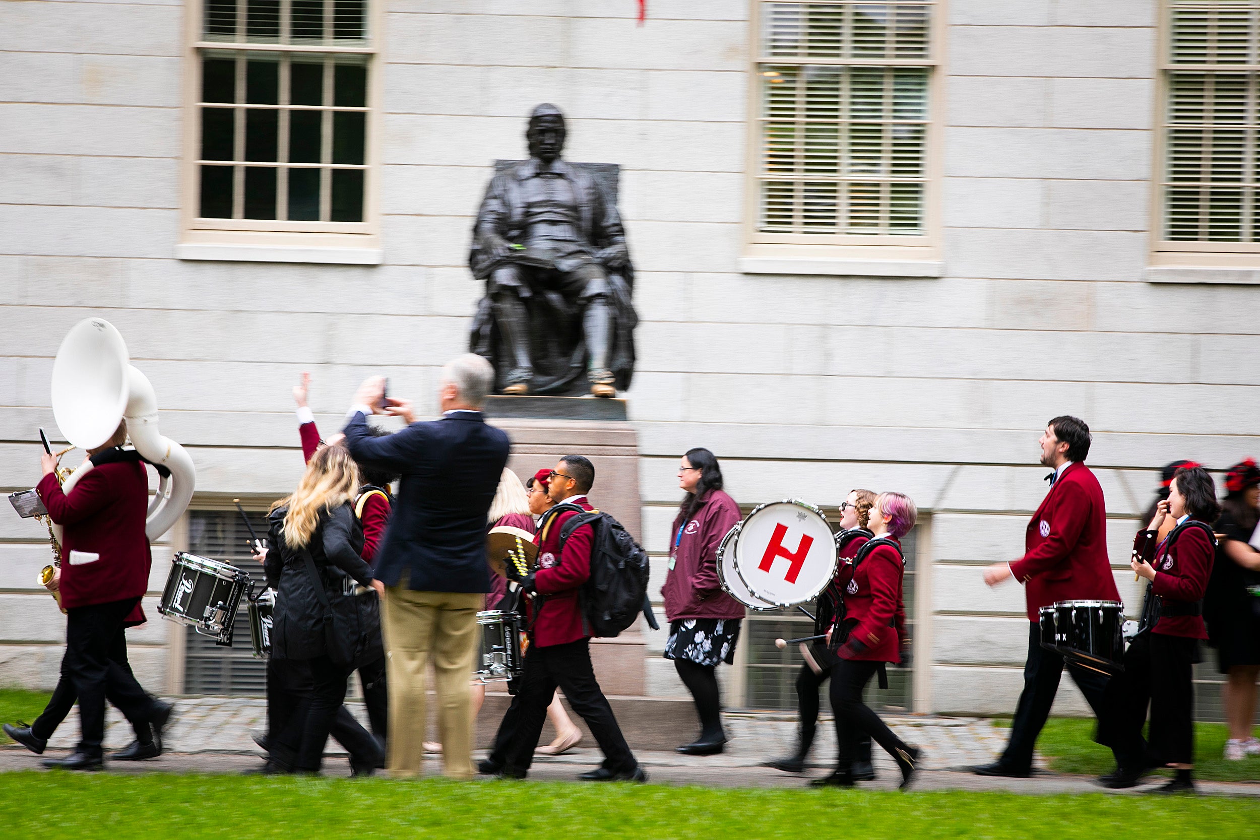 The Harvard Band marches by the John Harvard statues