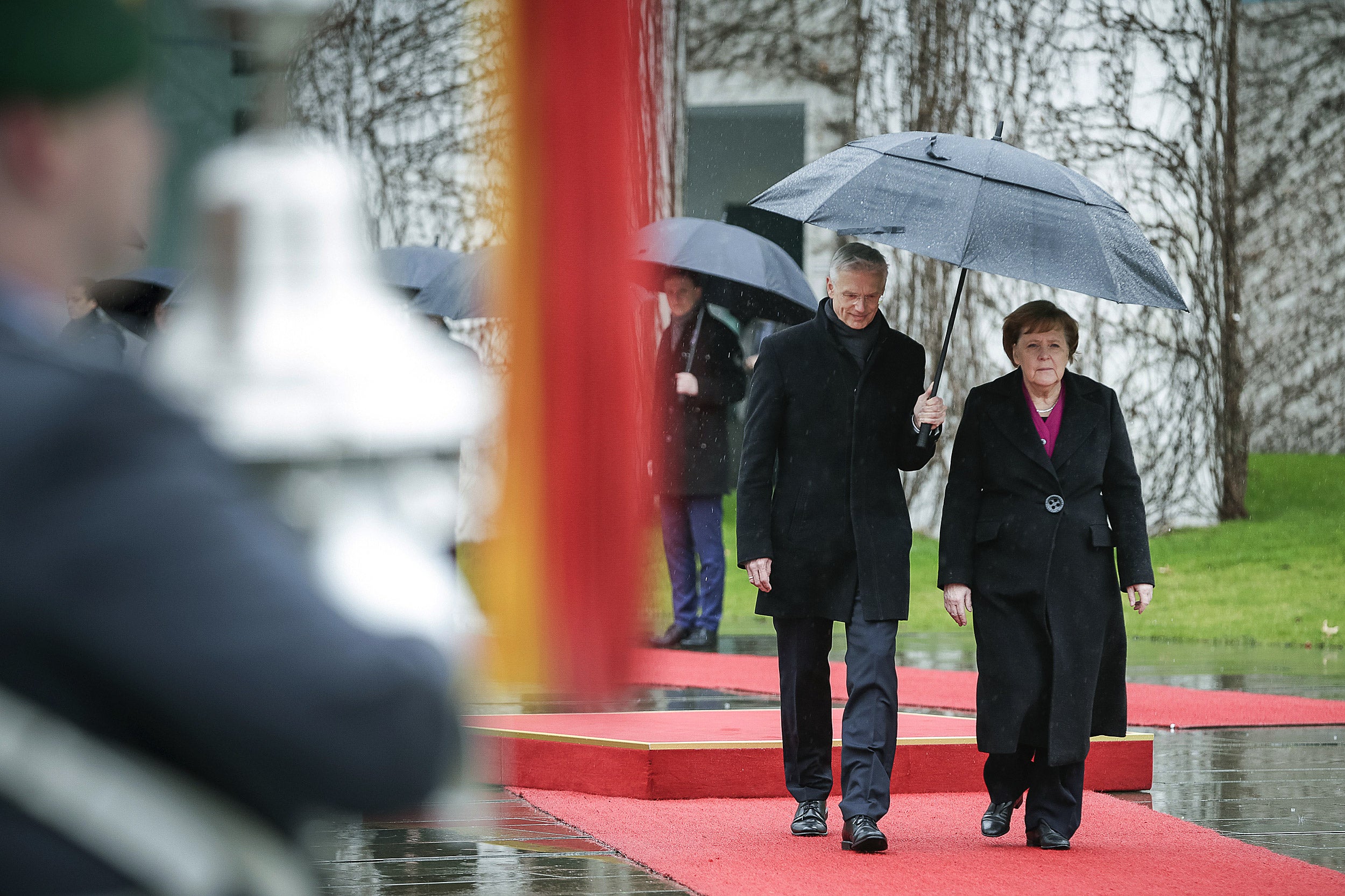 Angela Merkel walks under an umbrella with Krisjanis Karins, prime minister of Latvia.
