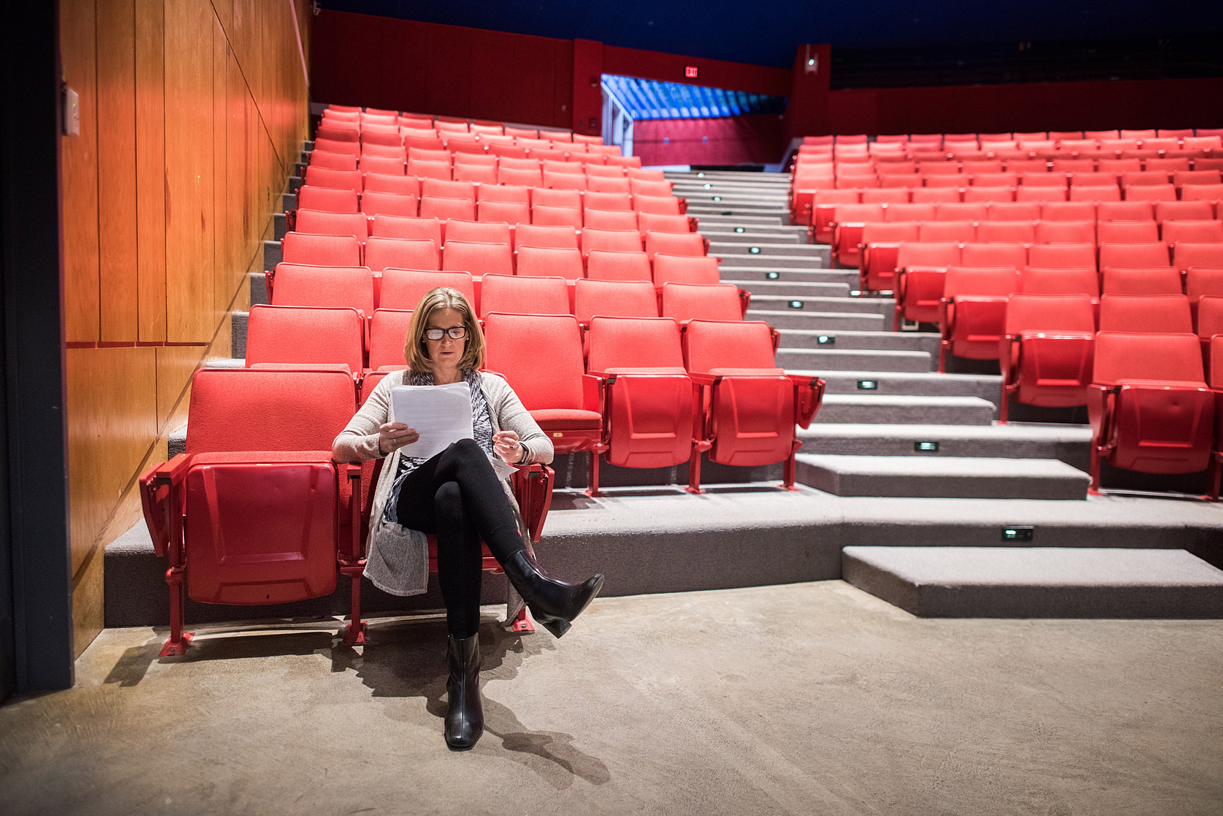 Dean Katie O'Dair sits in an empty theater preparing for a charity comedy night.