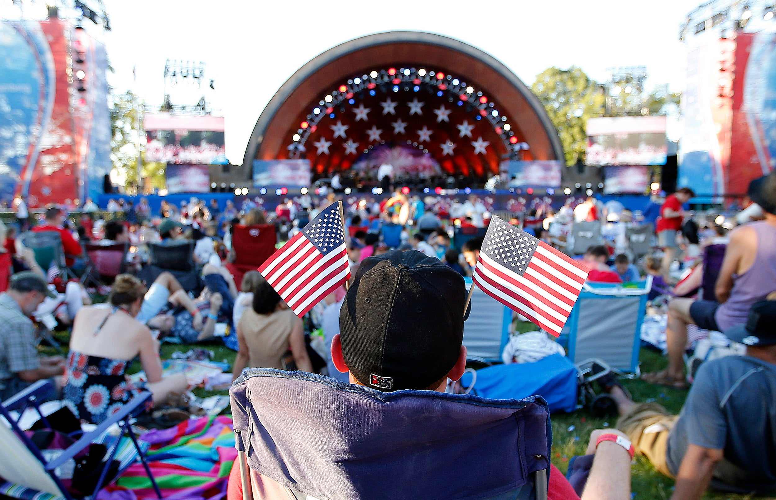 Man with American flags in his baseball cap, facing the Hatch Shell