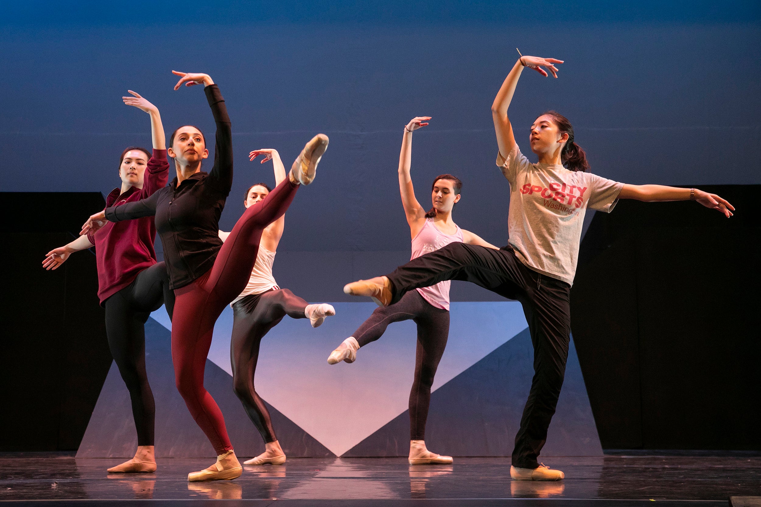 Five dancers pose with arms and legs outstretched.
