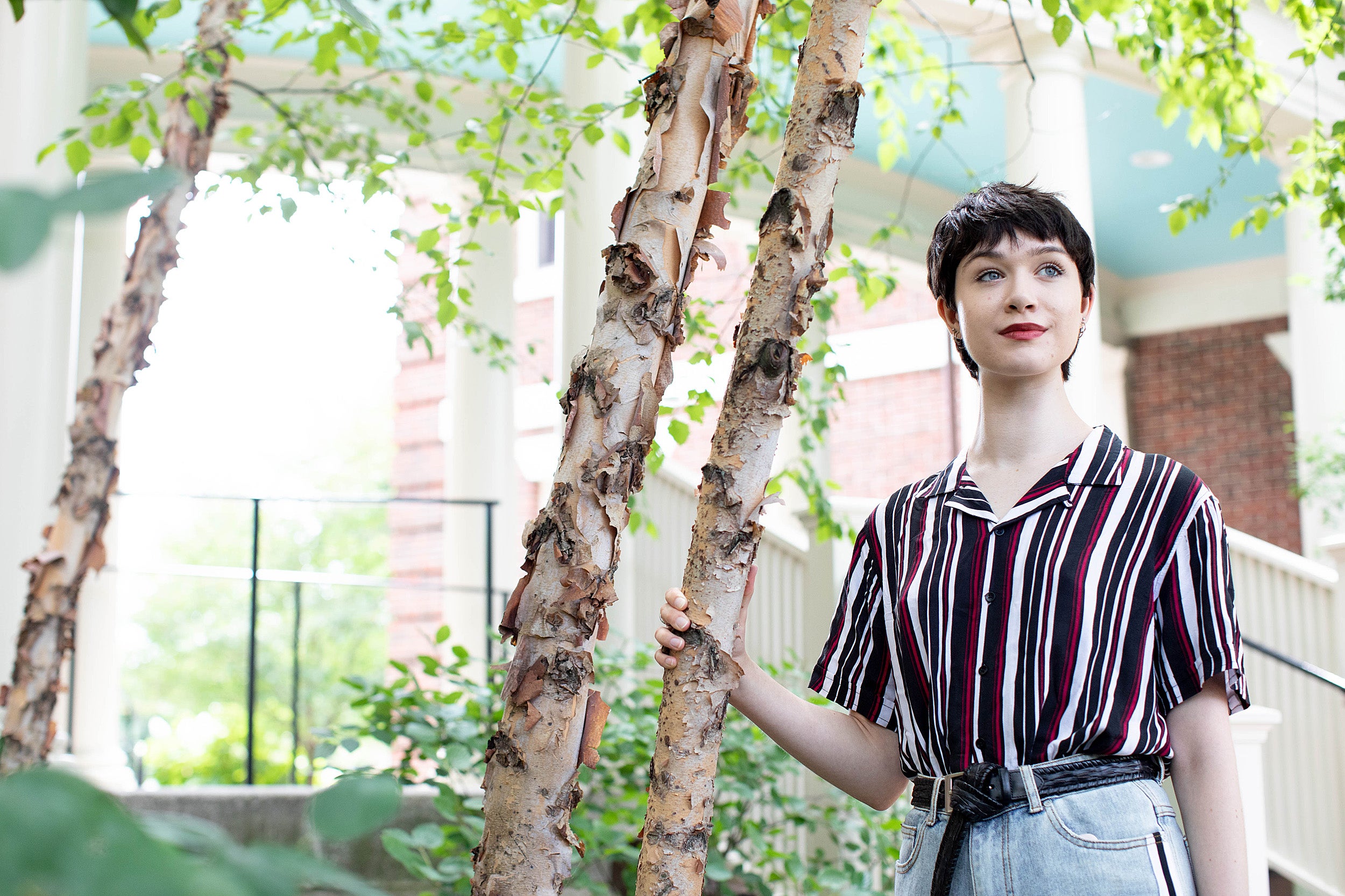 student in a striped shirt next to a tree