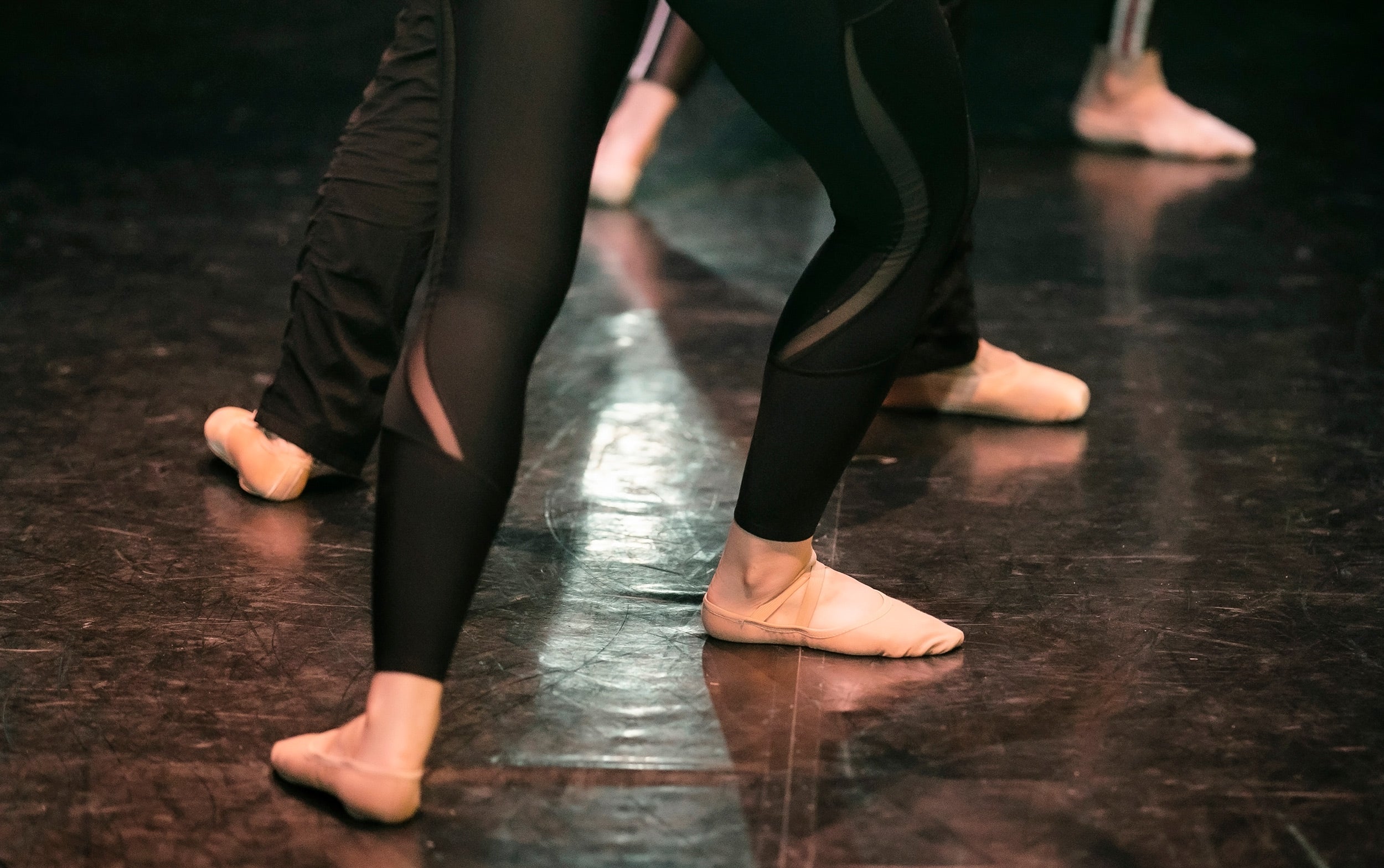 Detail of ballet dancers placing feet in fourth position.