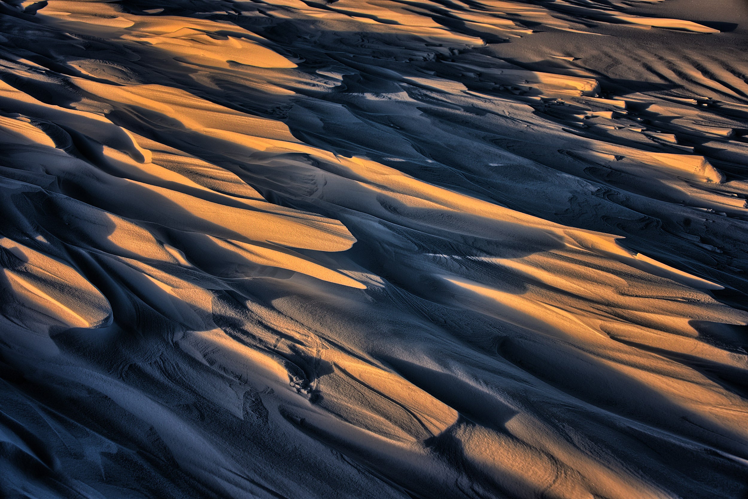 Dune-like formations sculpted by the wind called Sastrugi cast shadows on ice.