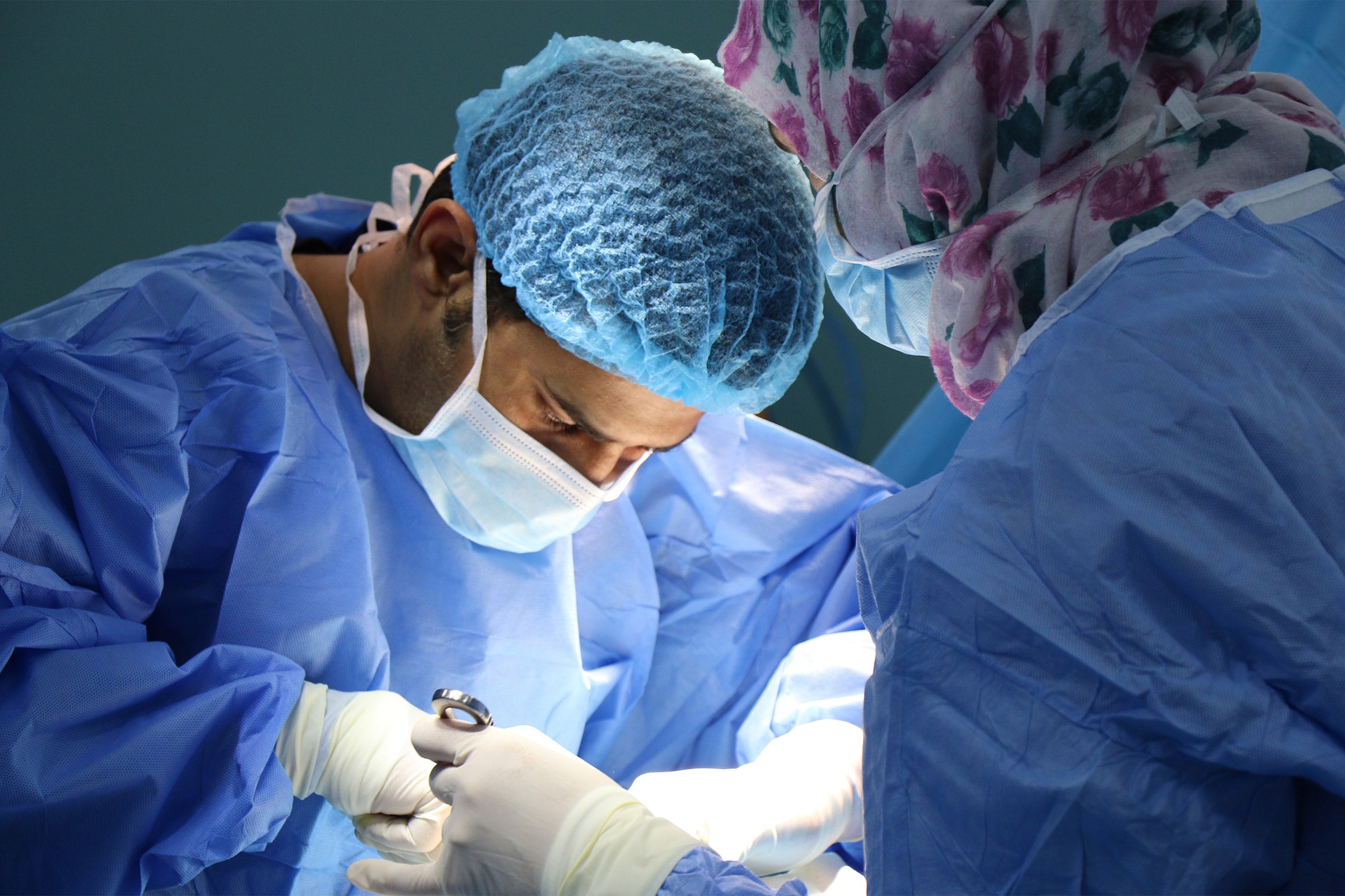 Doctor performing surgery, nurse in head a hijab or headscarf.