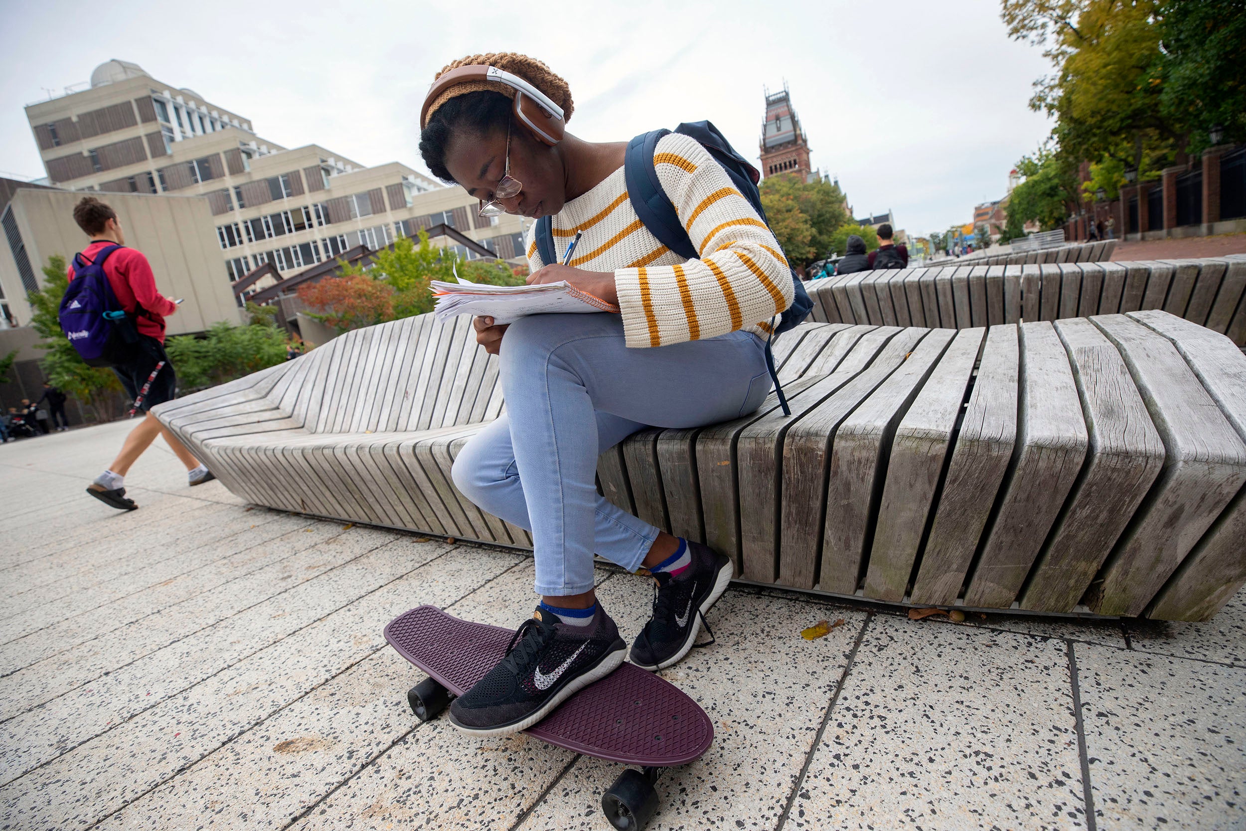 Edith “Tomi” Siyanbade does homework at the Science Center Plaza, resting her foot on a skateboard that she uses for transportation.