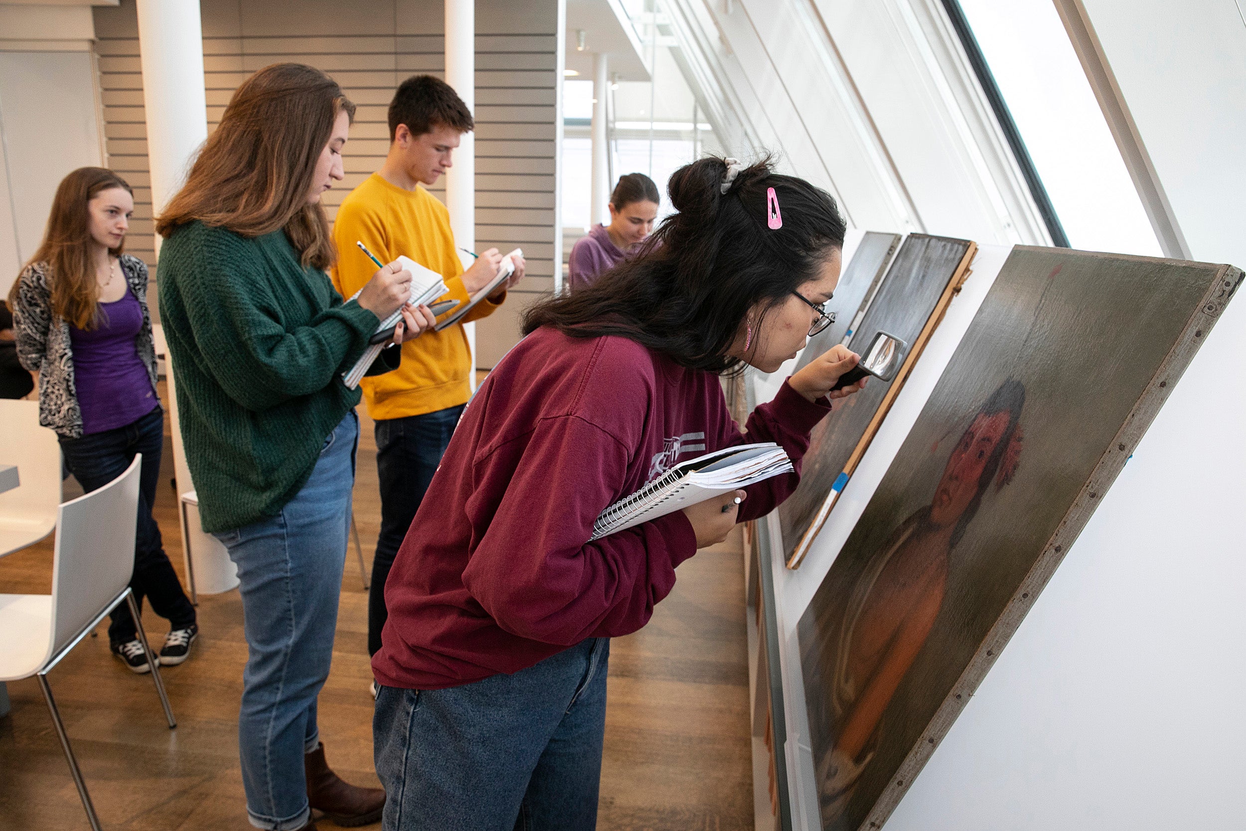students study oil paintings with magnifying glasses