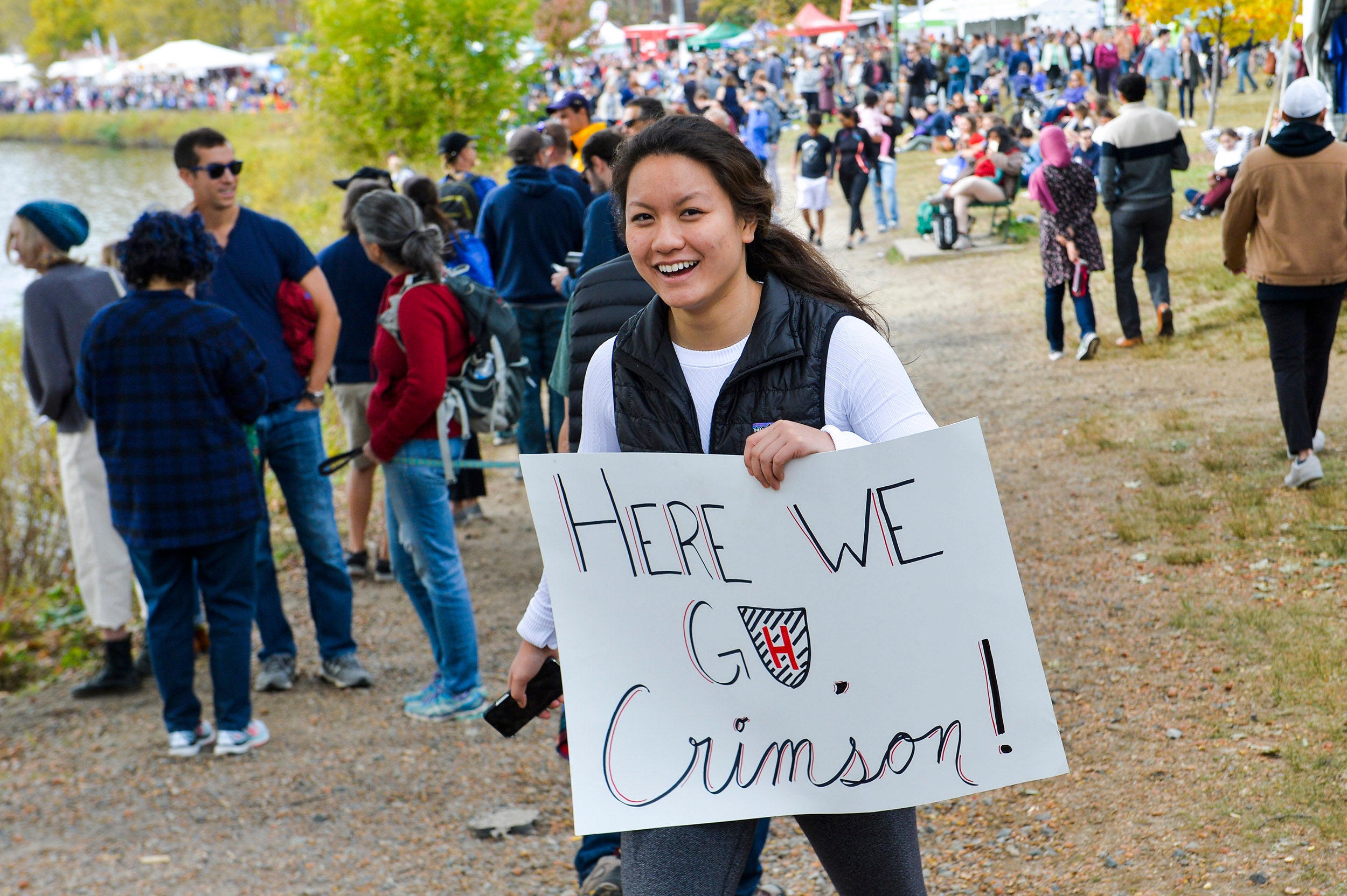 Student Athena Ye holds a sign "Here we go Crimson" during Head of the Charles weekend.