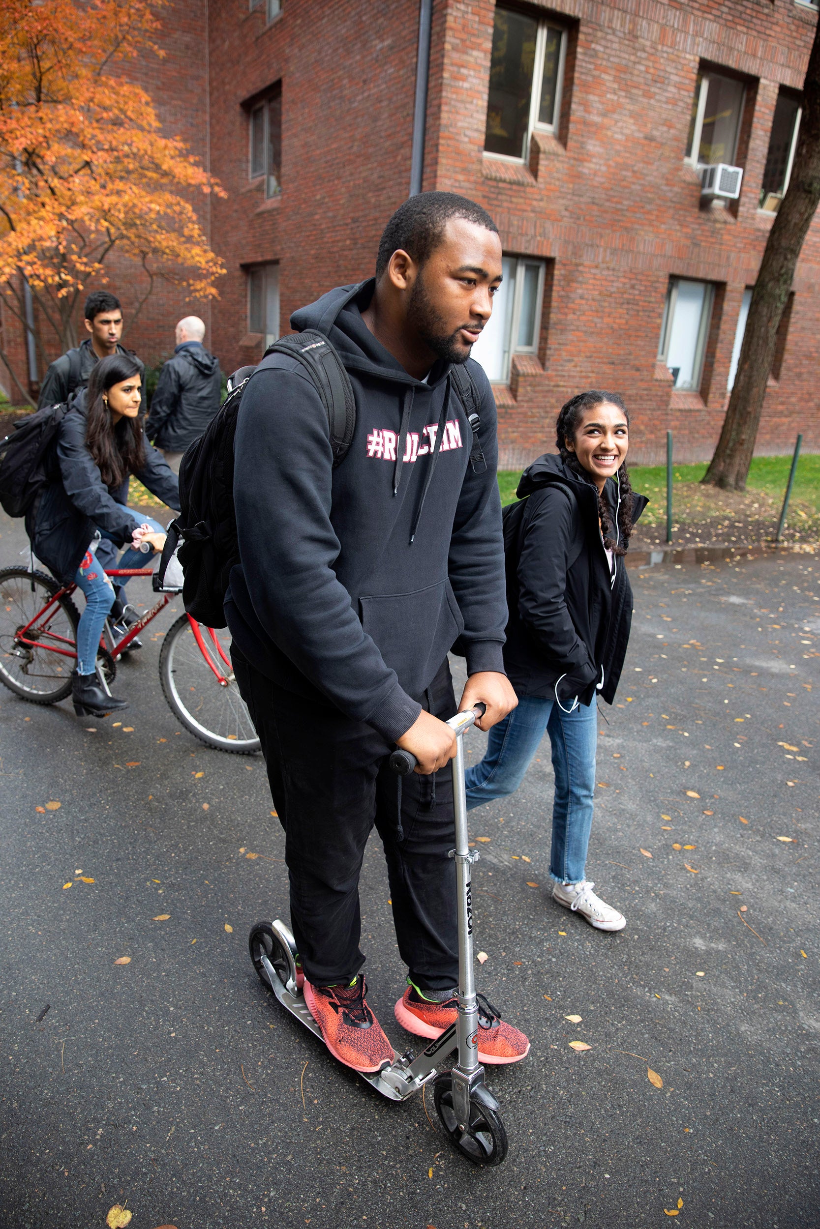 Jacob Sykes rides his scooter, and Noor Kamal walks across campus.