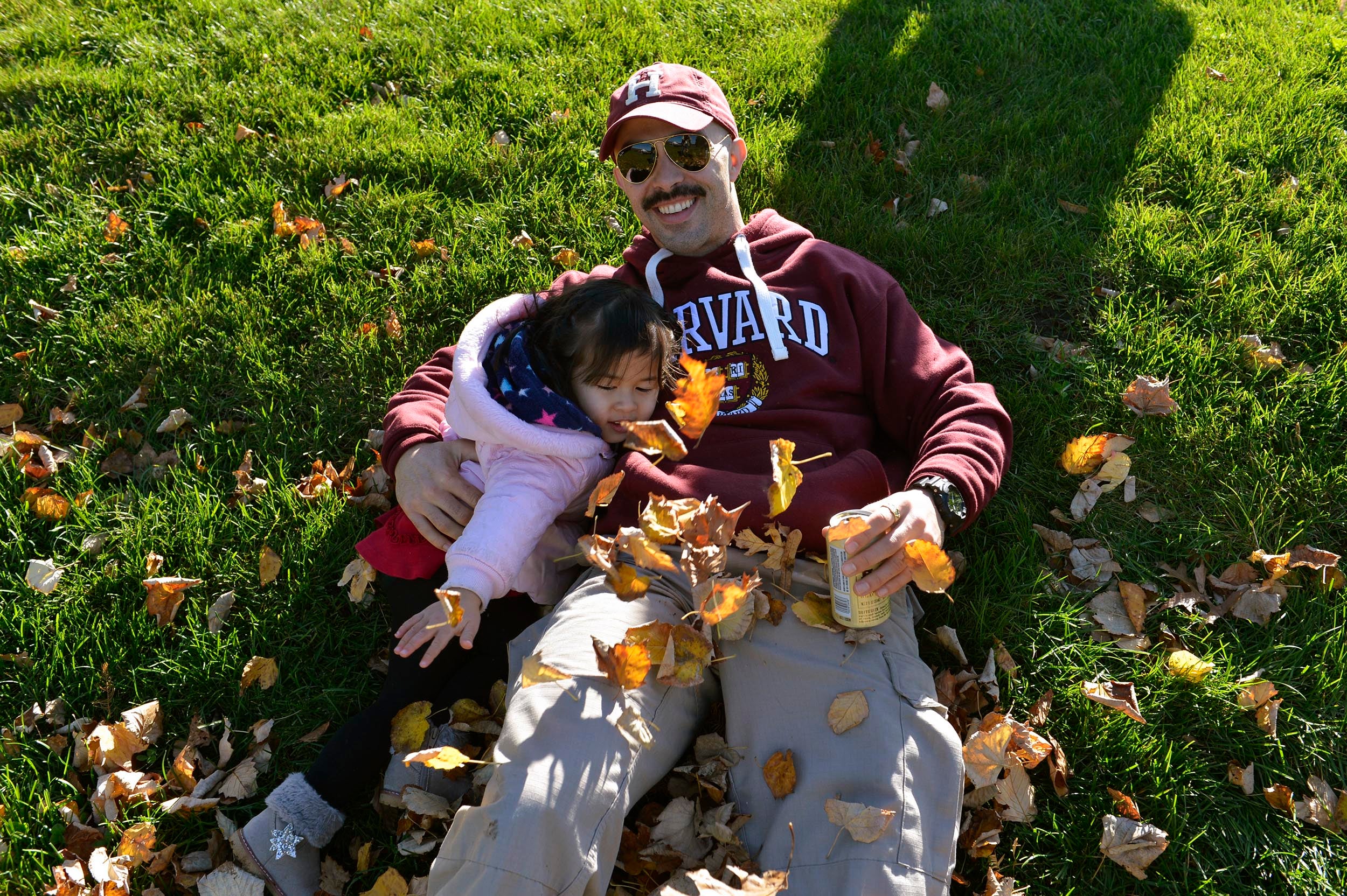 Nicholas Nesbit from Harvard Extension School rolls in the autumn leaves with his daughter Roisian, 2.