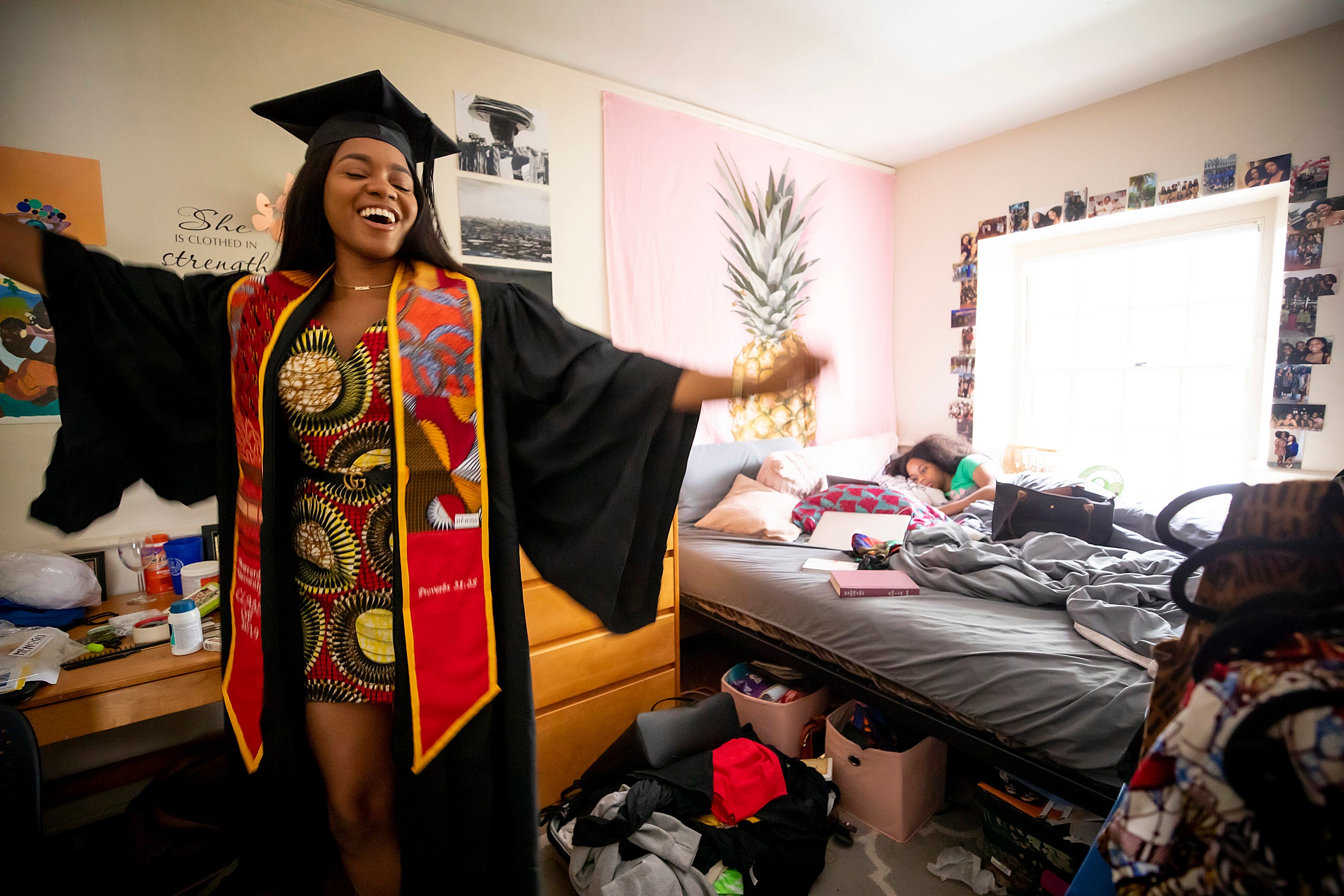 A graduate celebrates while her sister lies in bed.