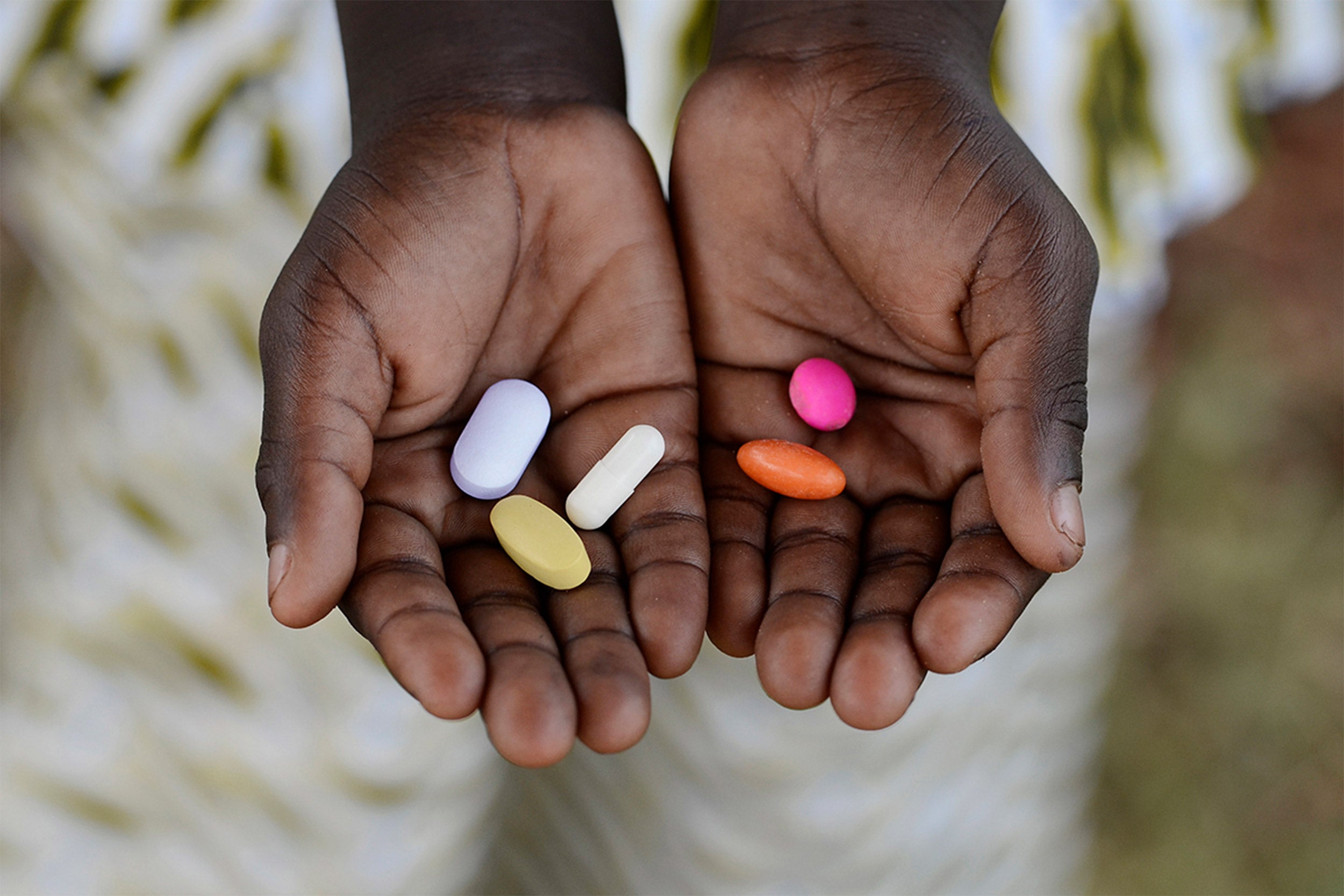Black African boy holding antibiotic pills.