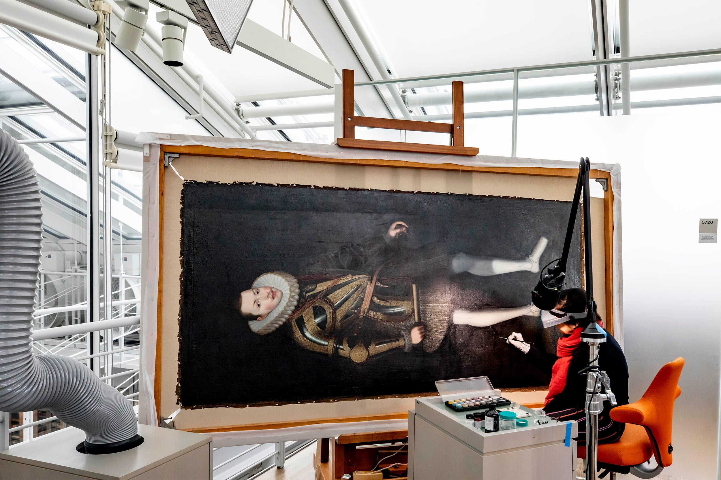 Curator restores a large painting.
