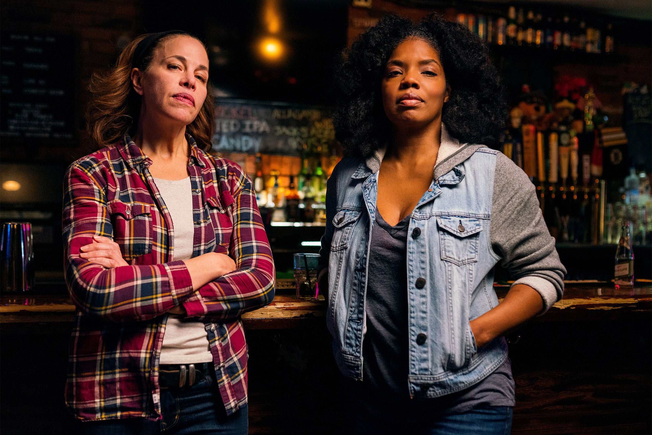 Two women standing in a bar.