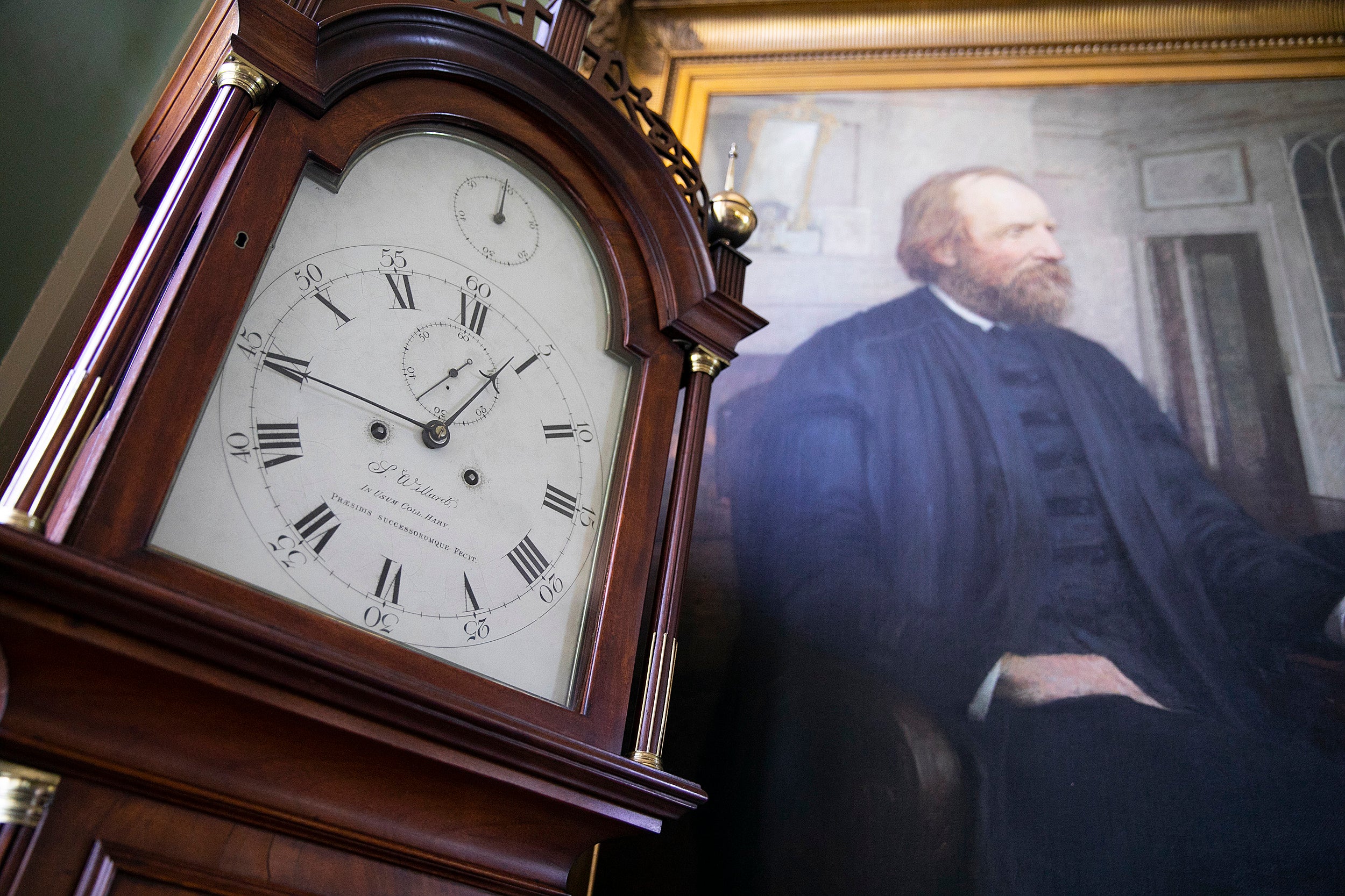 Clock next to a portrait.