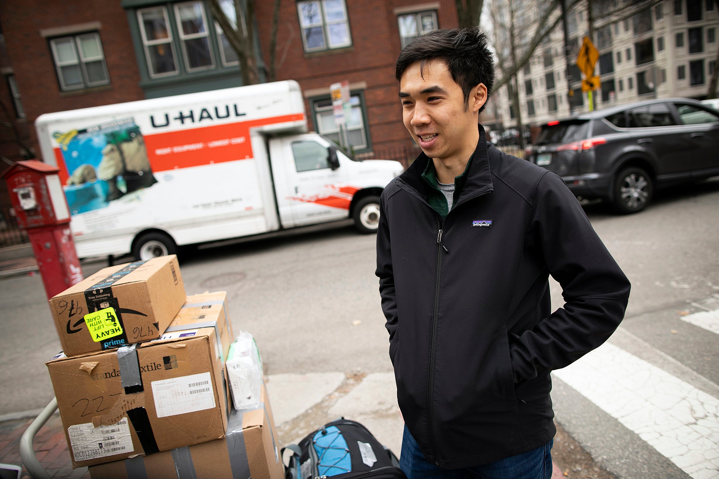 Victor Qin stands with boxes by a moving truck.