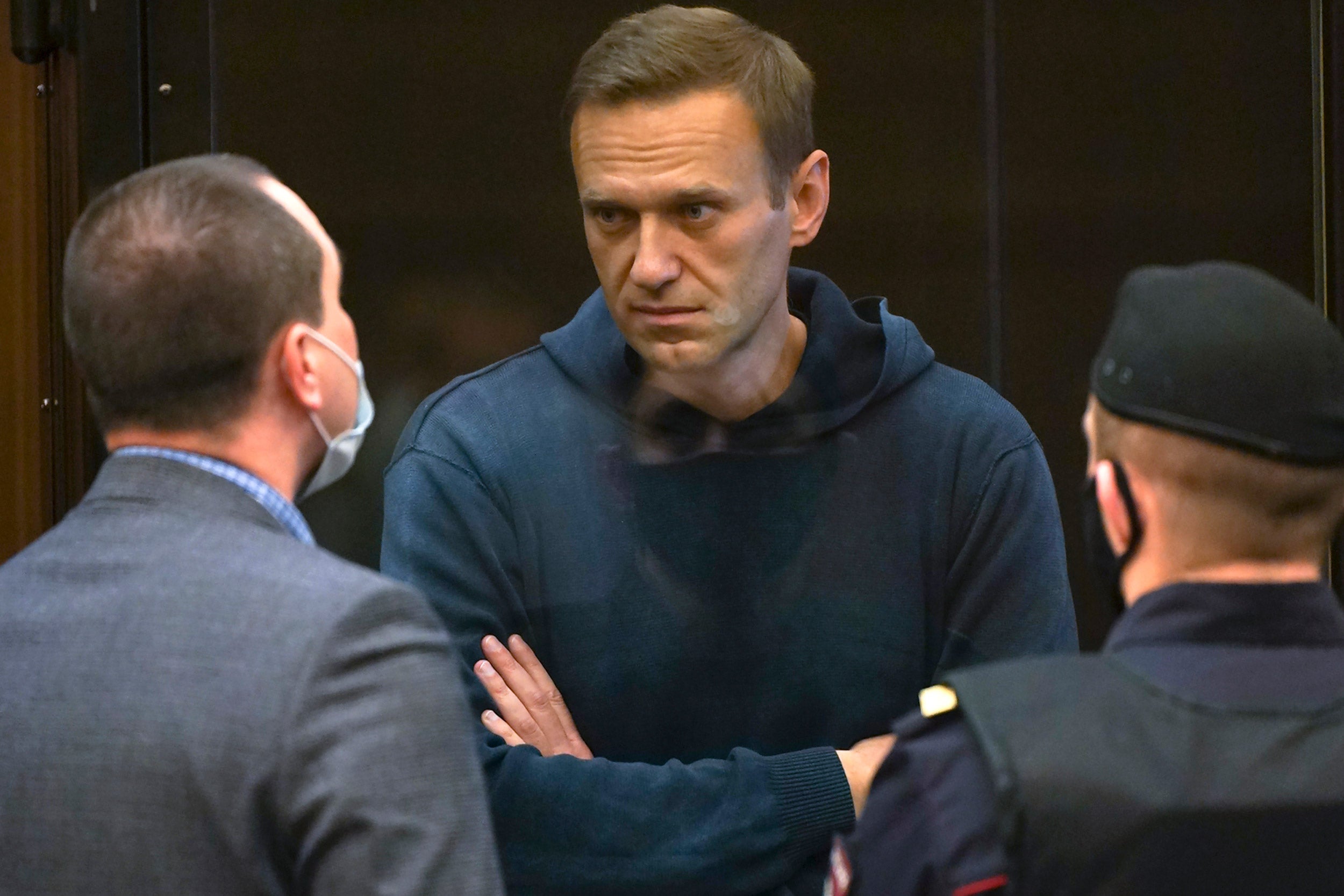 Alexei Navalny talks to one of his lawyers, left, while standing in the cage.