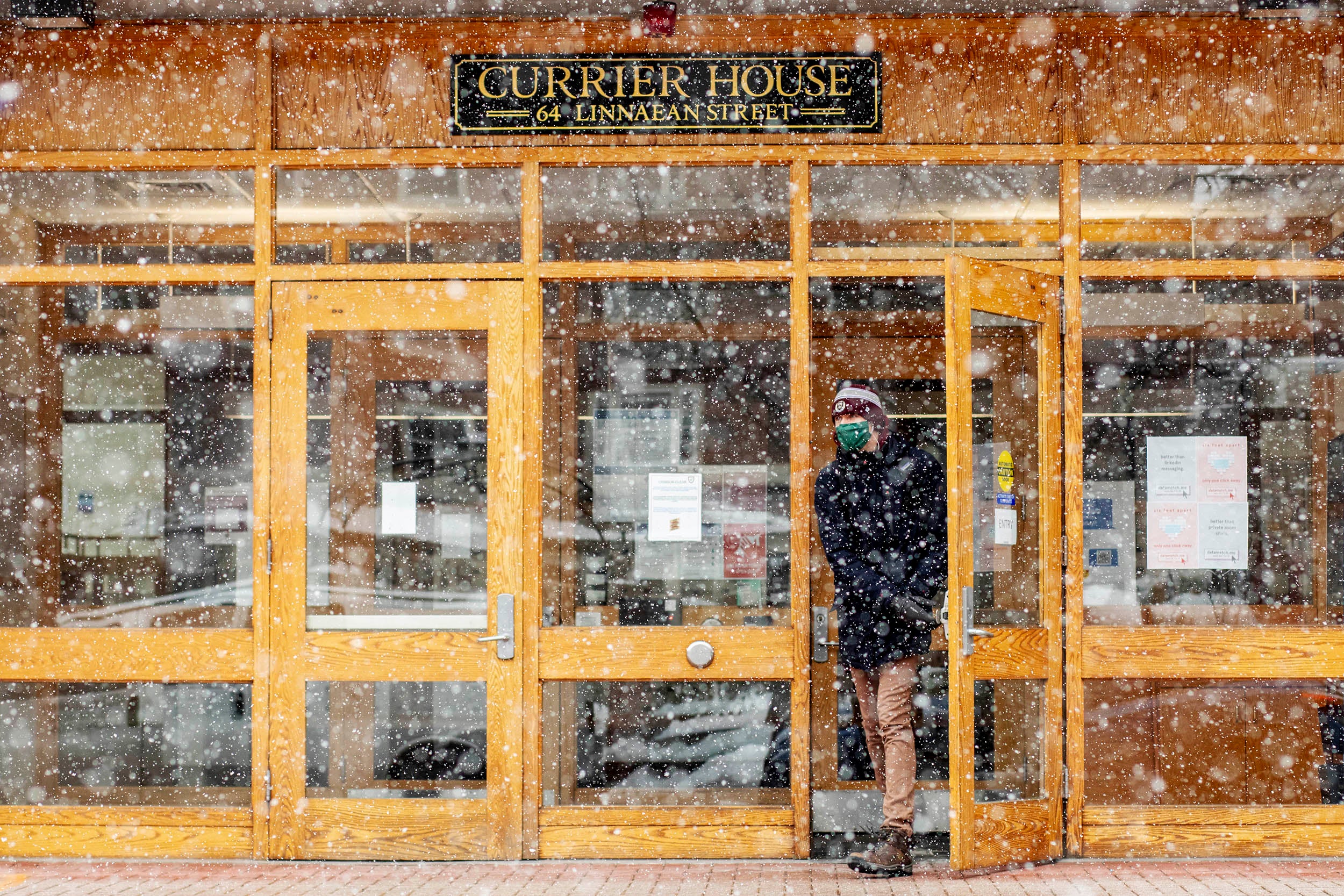 A student leaving Currier’s main entrance braves the snow.