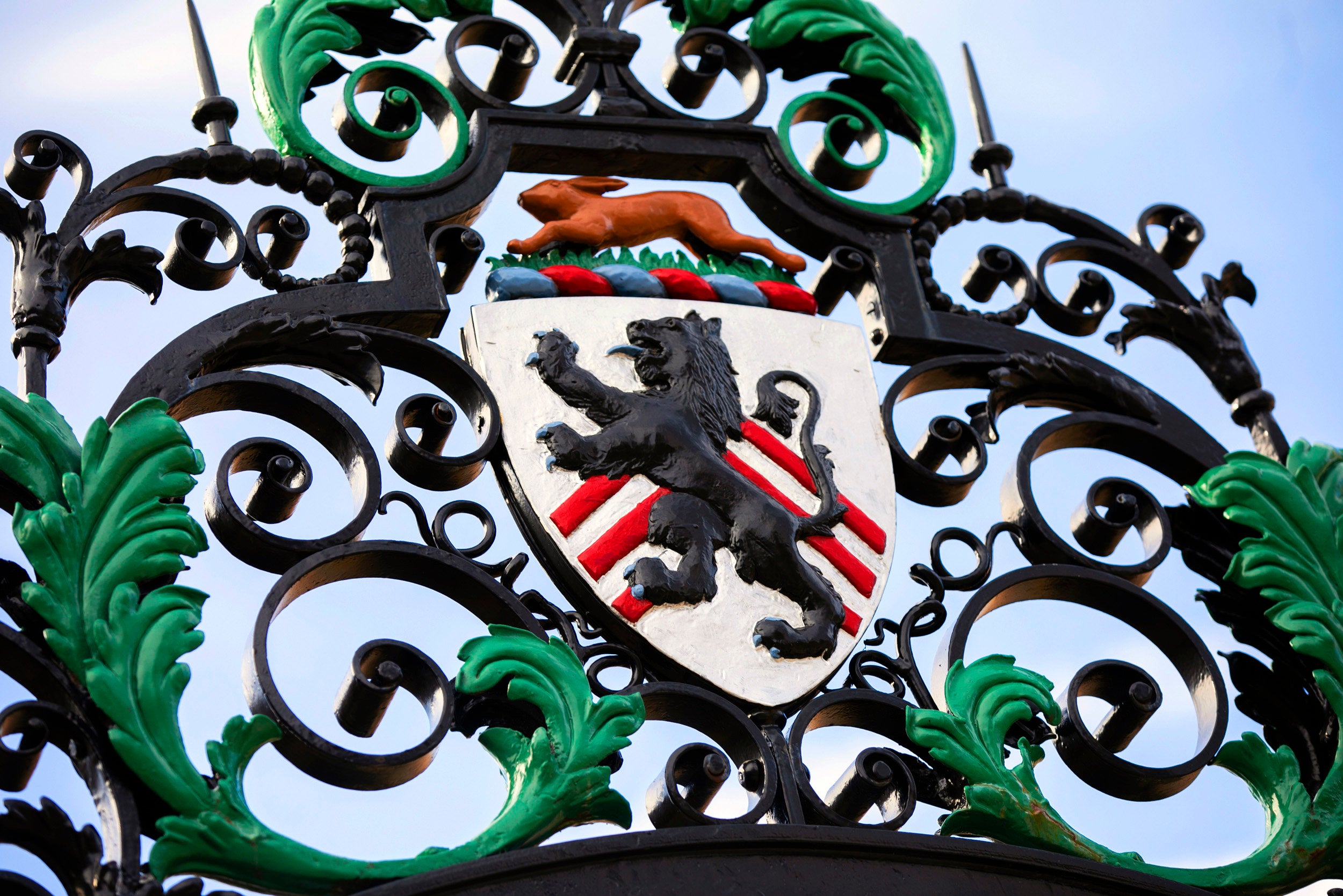 A rabbit leaps over the lion crest on the wrought-iron gate.