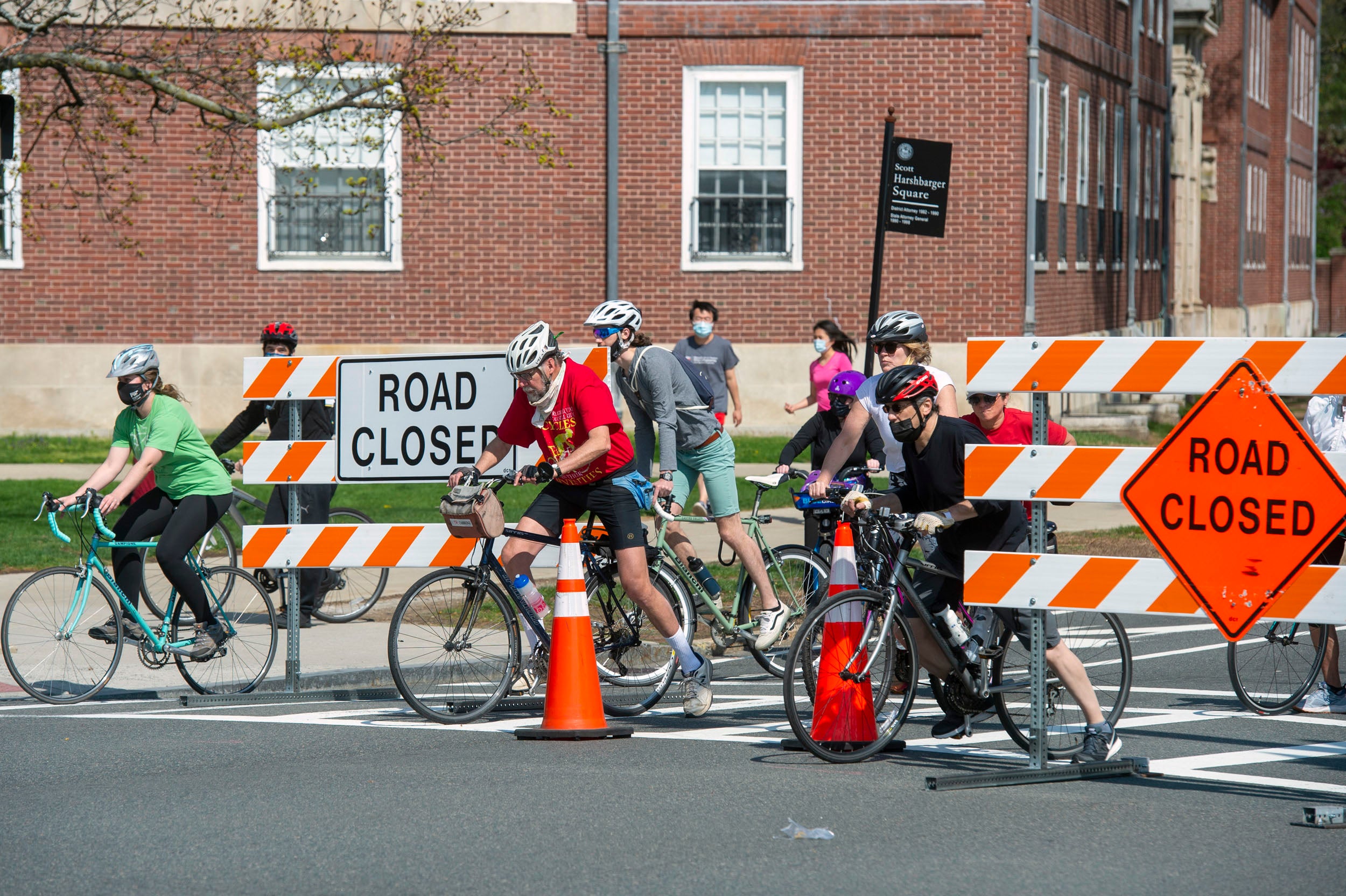 Bicyclists wait for the light at JFK Street next to a barricade on Mem Drive.