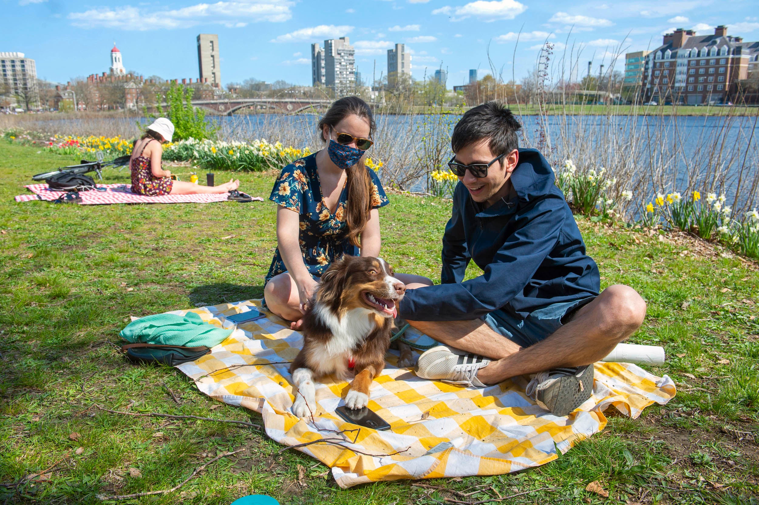 Karen Mata and Rodrigo Guerra relax along the Charles River with their dog.