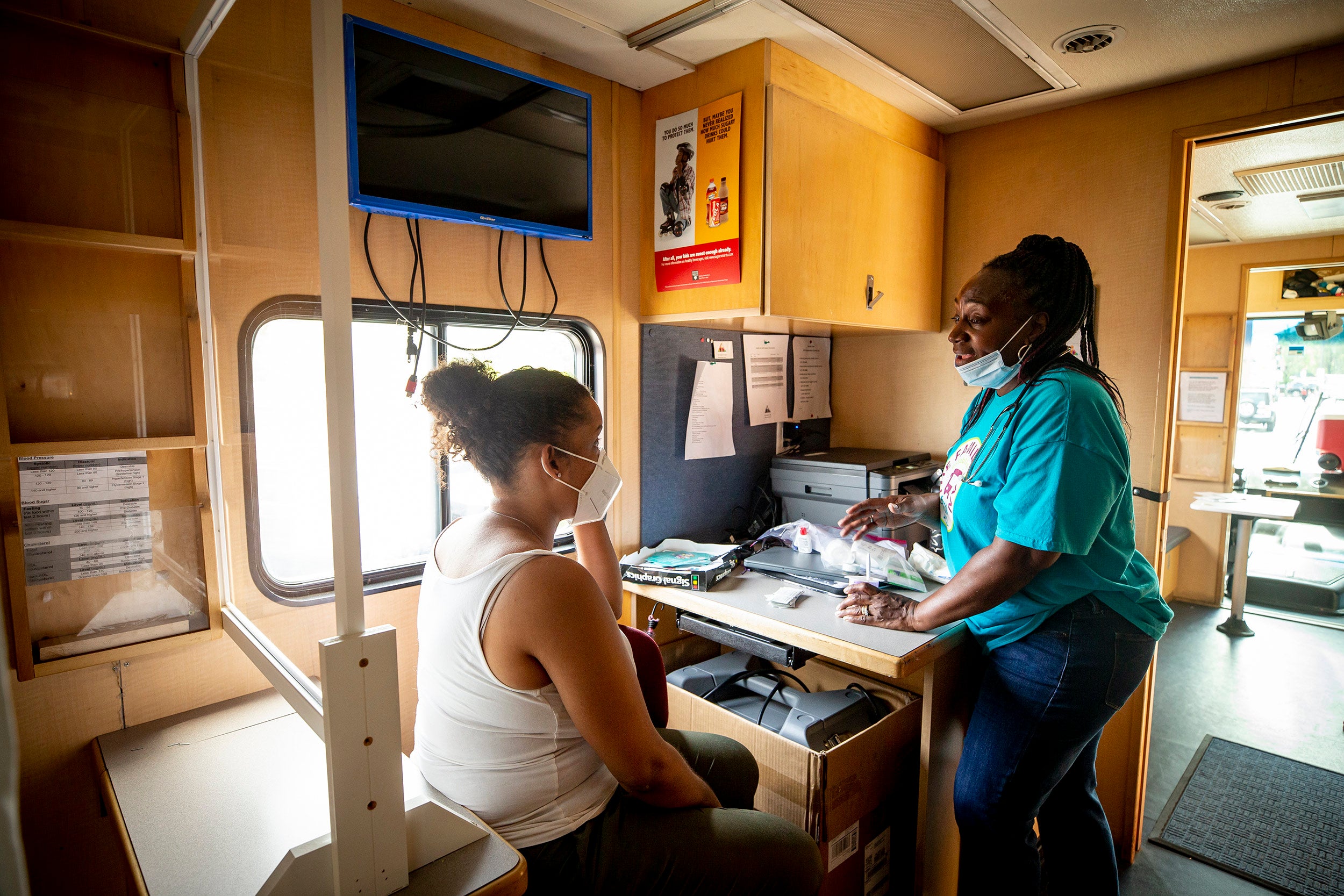 Rainelle Walker White, right, assistant director, while eating her lunch, chats with staffer Joanne Suarez inside Harvard University's Family Van.