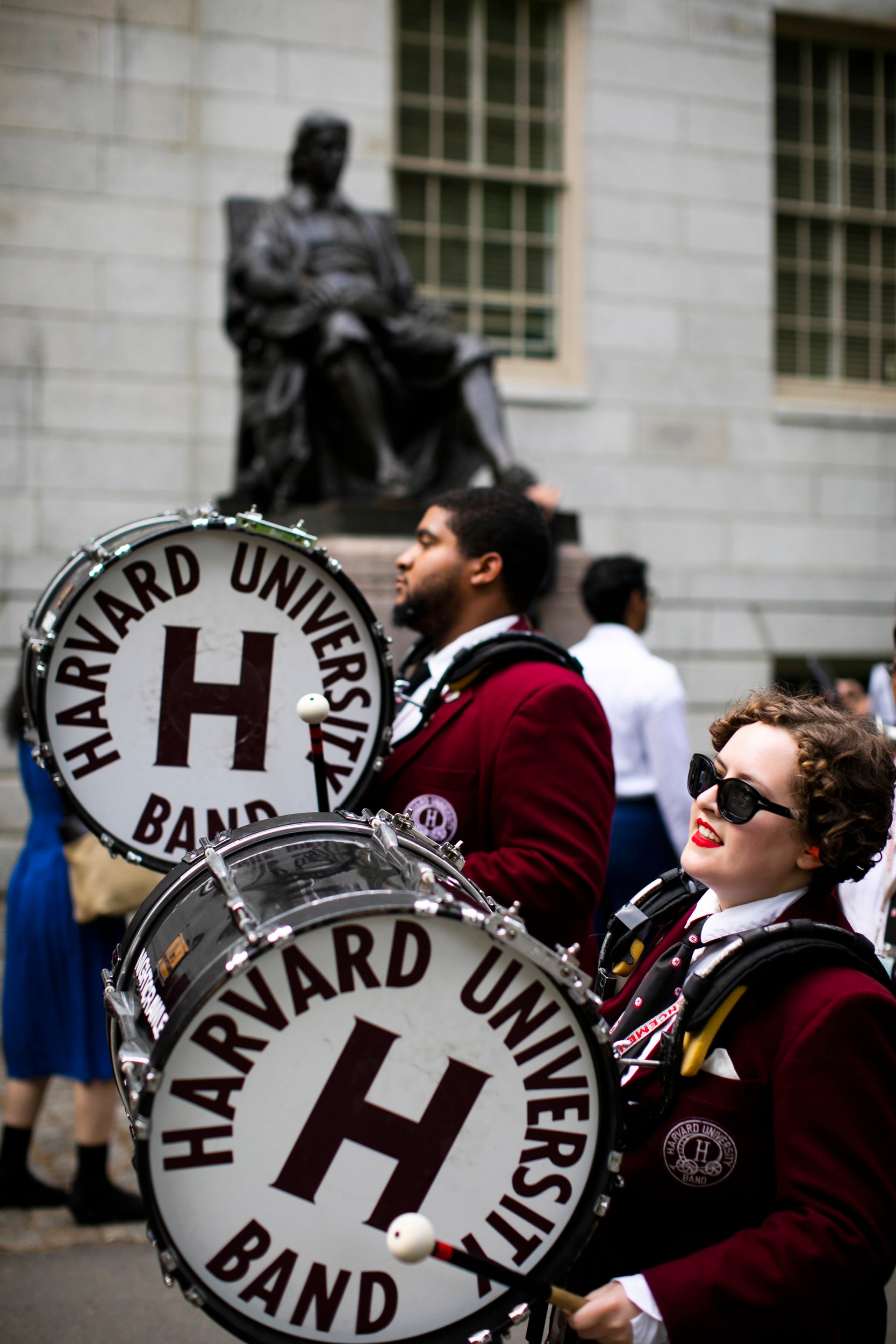 Harvard Band drummers pass the John Harvard Statue.