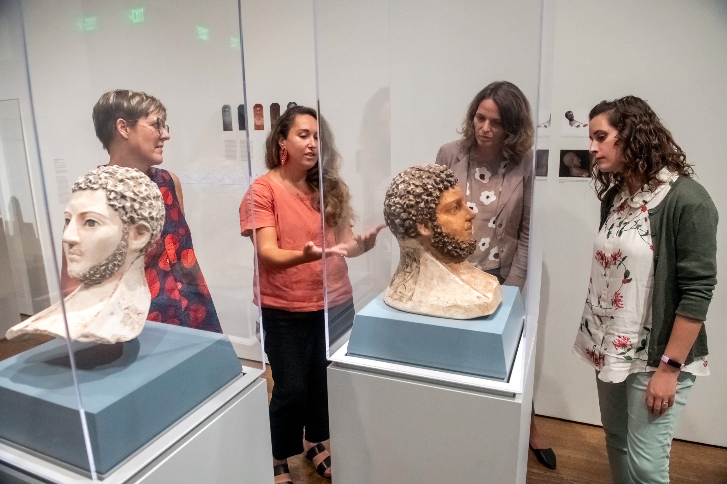 Curators Kate Smith, Jen Thum, Susanne Ebbinghaus, and Georgina Rayner with funerary masks displayed in glass cases.