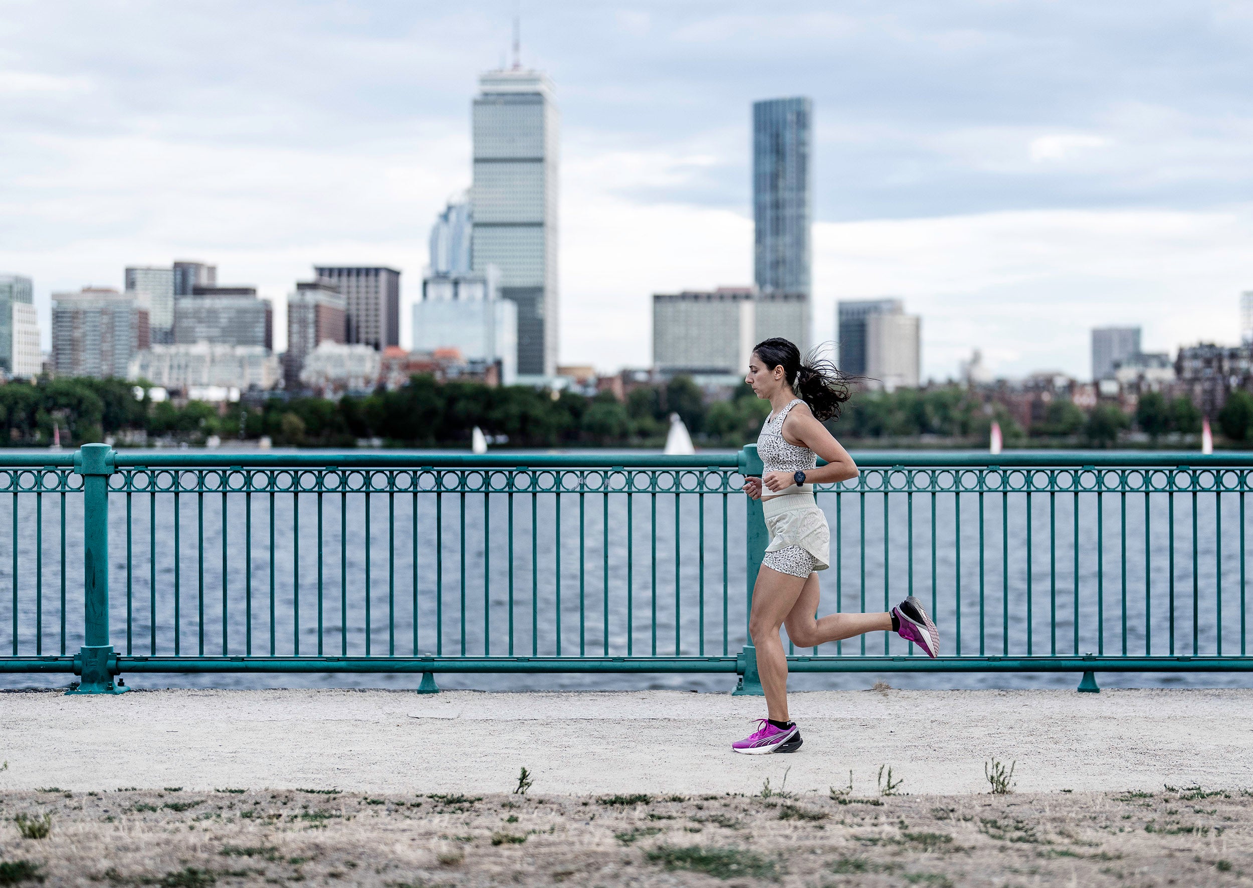Alia Qatarneh runs along Charles River with Boston skyline in background.