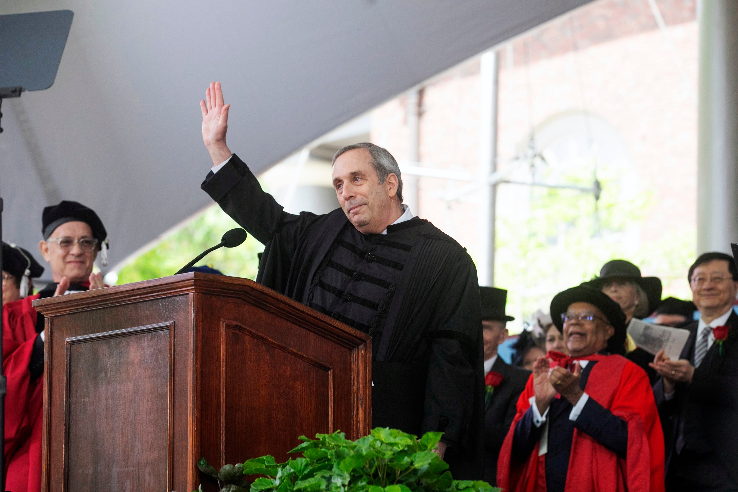 Larry Bacow waves at podium.