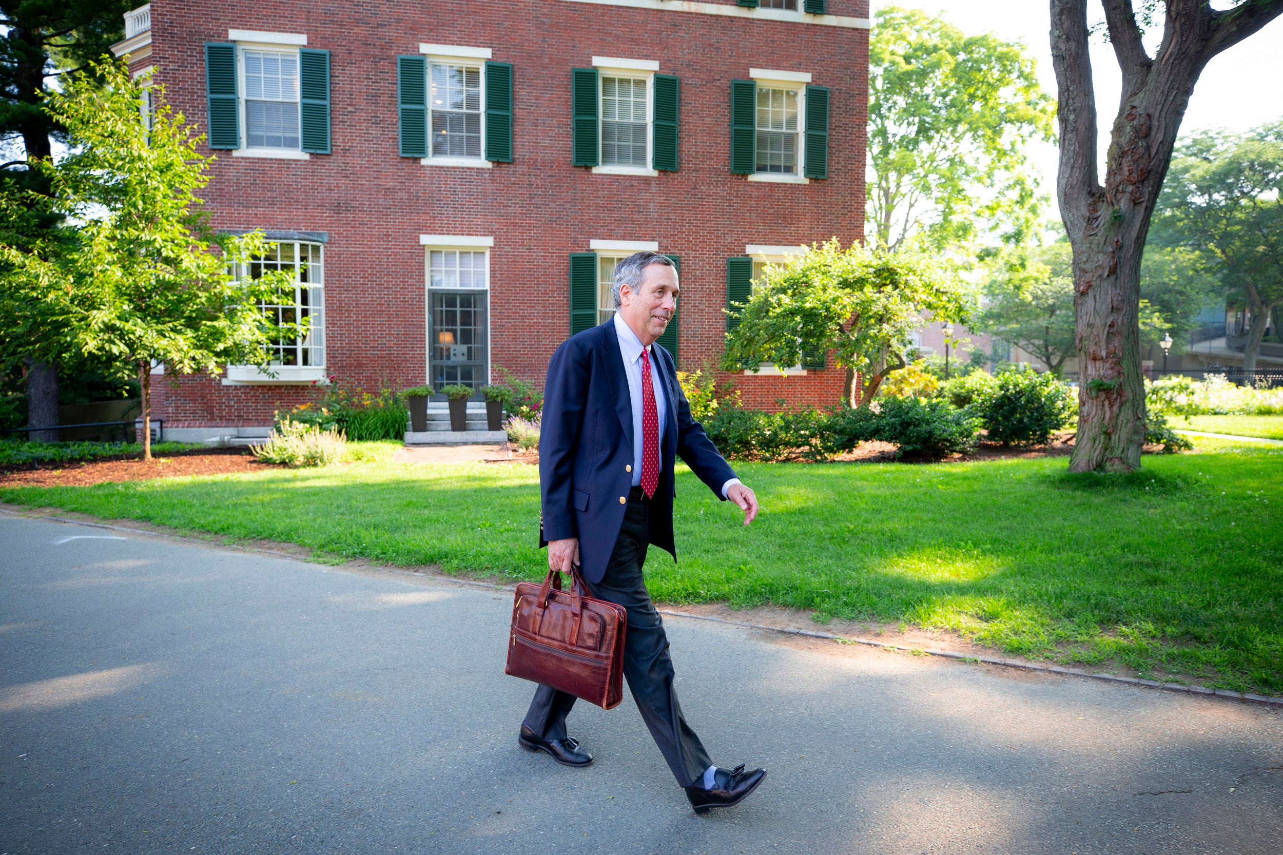 Larry Bacow walks past Loeb House on his first day on the job.