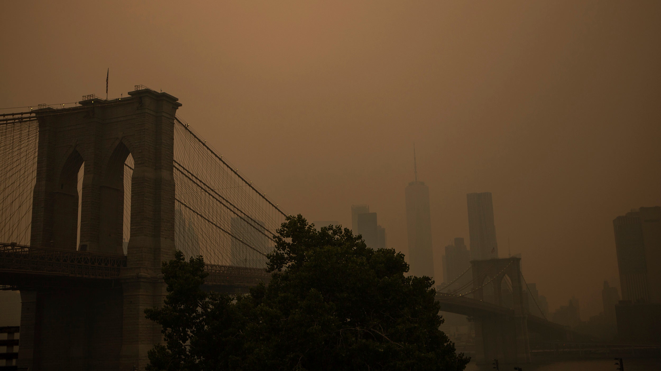 Orange haze over Brooklyn Bridge and New York City skyline.