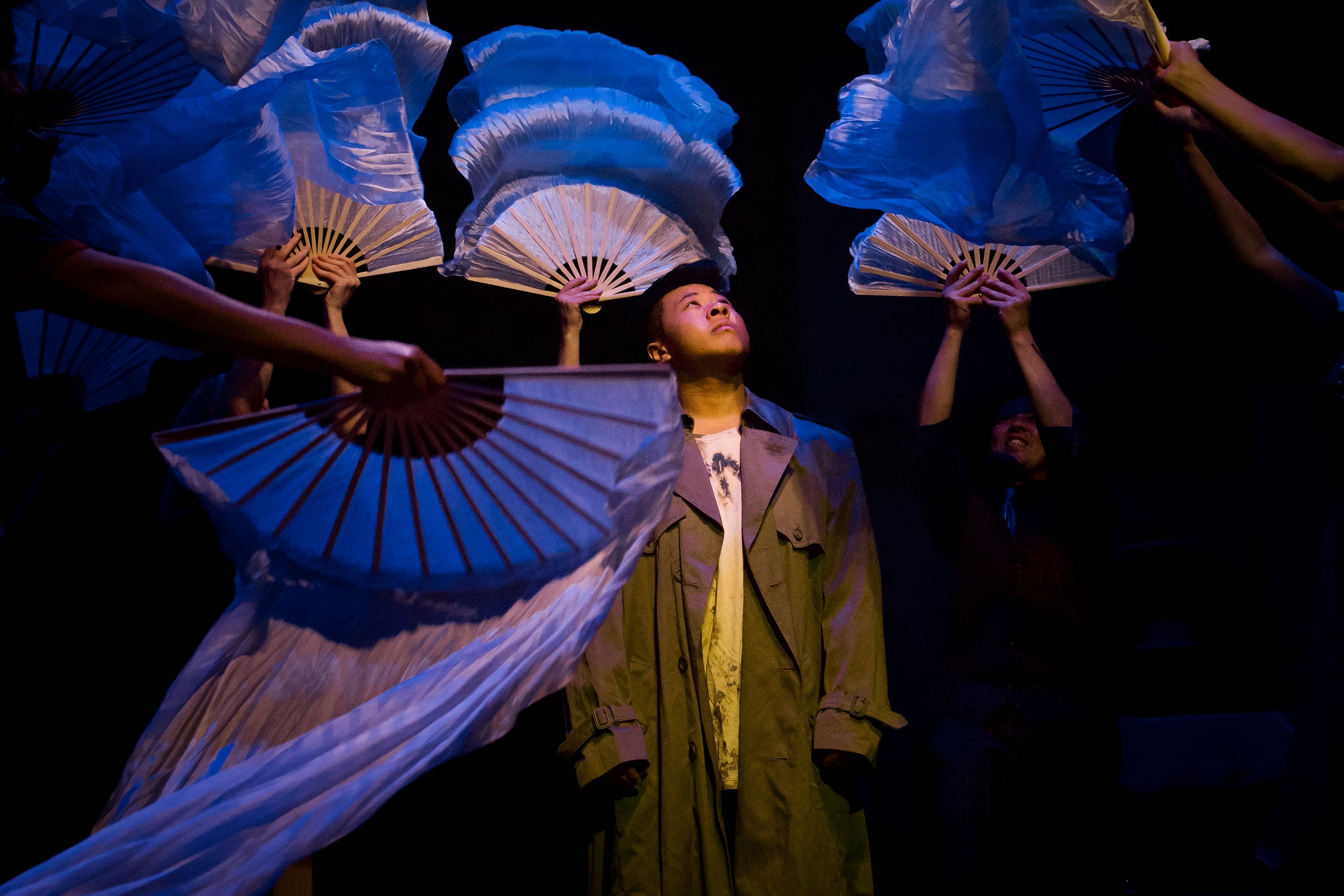 Richard (Jupiter Lê) in surrounded by fluttering fans in a scene from the play "SWAN."